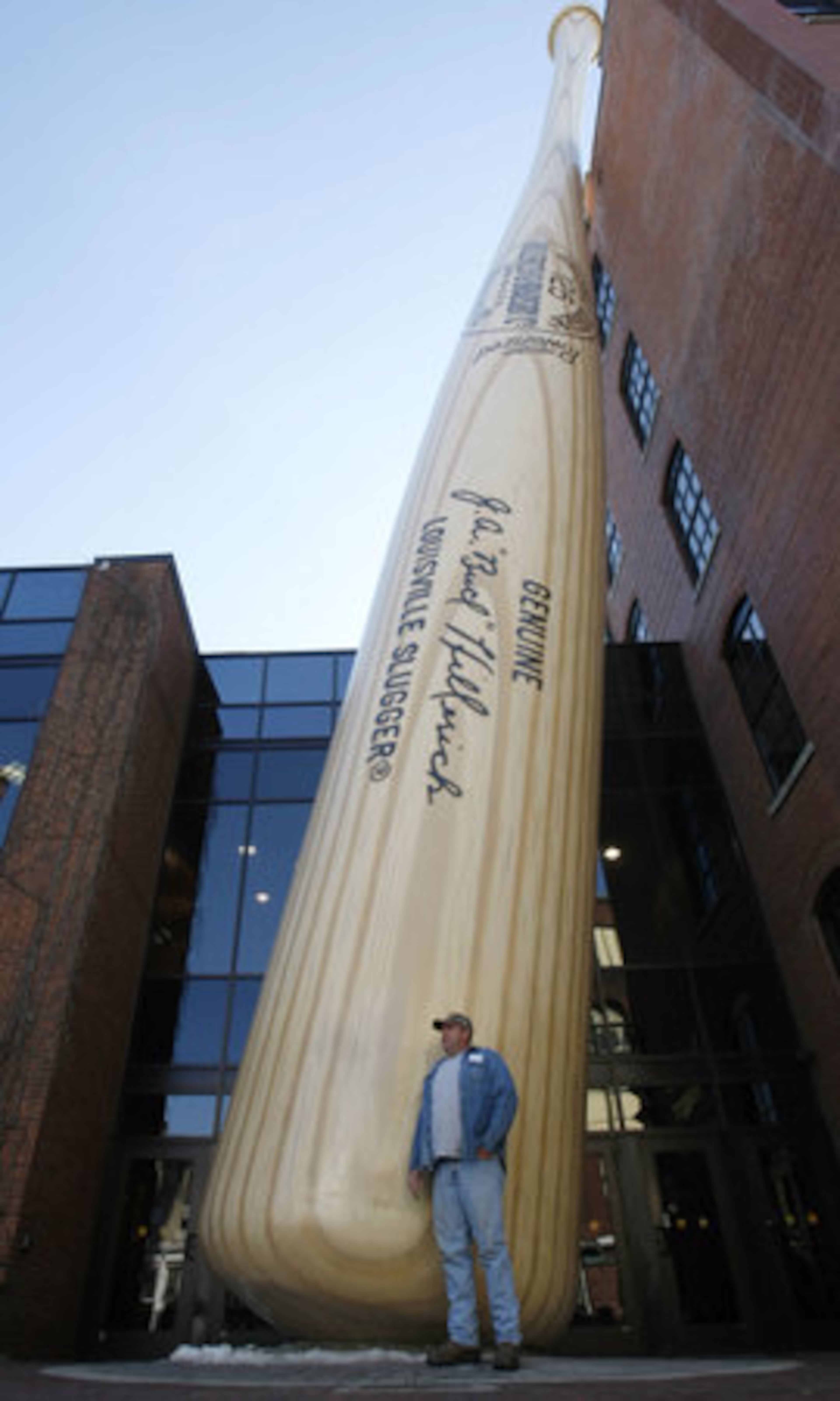 Bland McCall of Bennettsville, S.C., poses in front of a giant representation of the iconic Louisville Slugger bat at the Louisville Slugger Museum & Factory in Louisville, Ky.