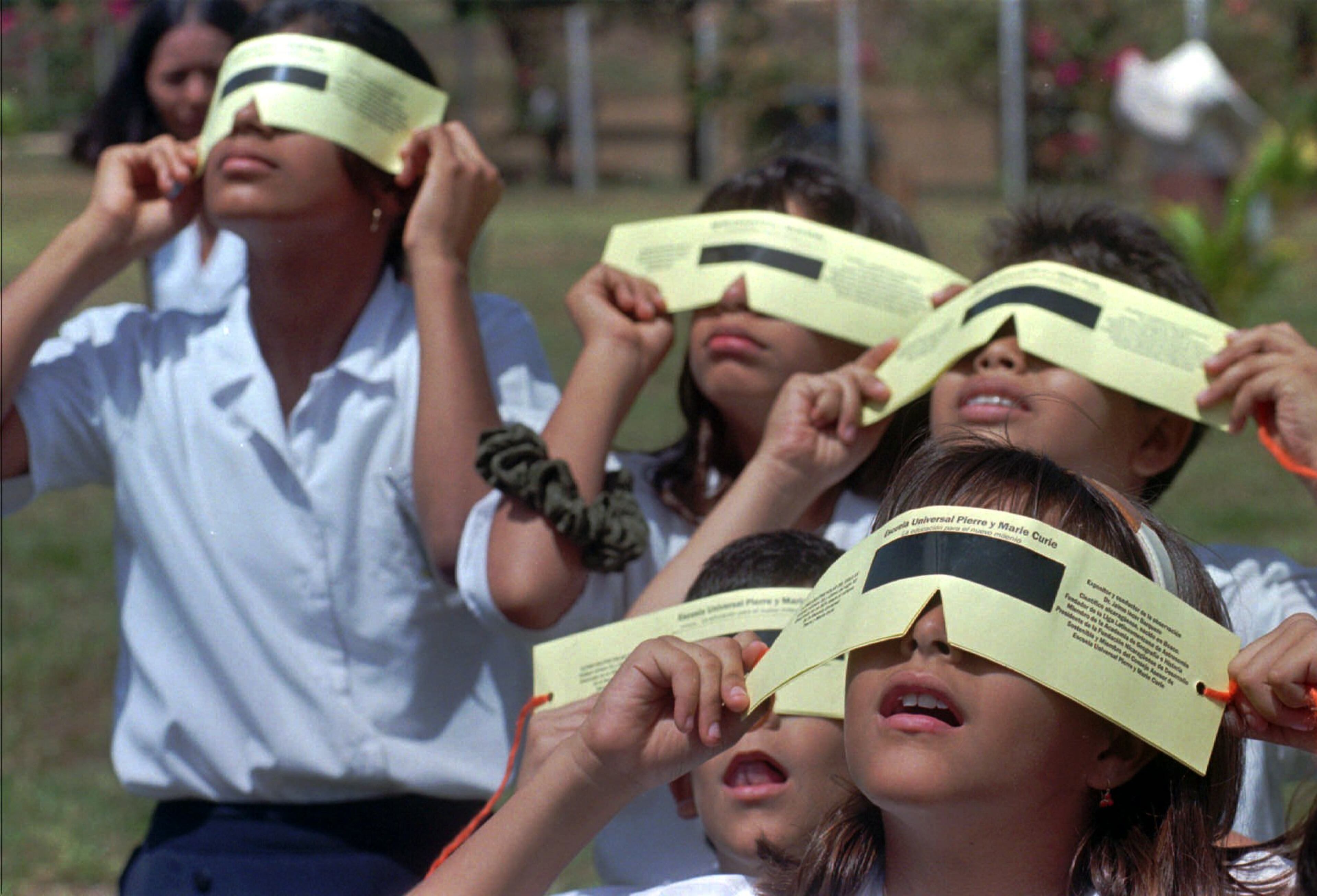 Nicaraguan students of the Pierre and Marie Currie school watch a partial eclipse of the sun through protective glasses in Managua Nicaragua, Thursday Feb. 26, 1998. While parts of Central America expierenced a partial eclipse of the sun a total eclipse, the last of the century in this hemisphere, was witnessed in parts of the Caribbean. (AP Photo/Tomas Stargardter)
