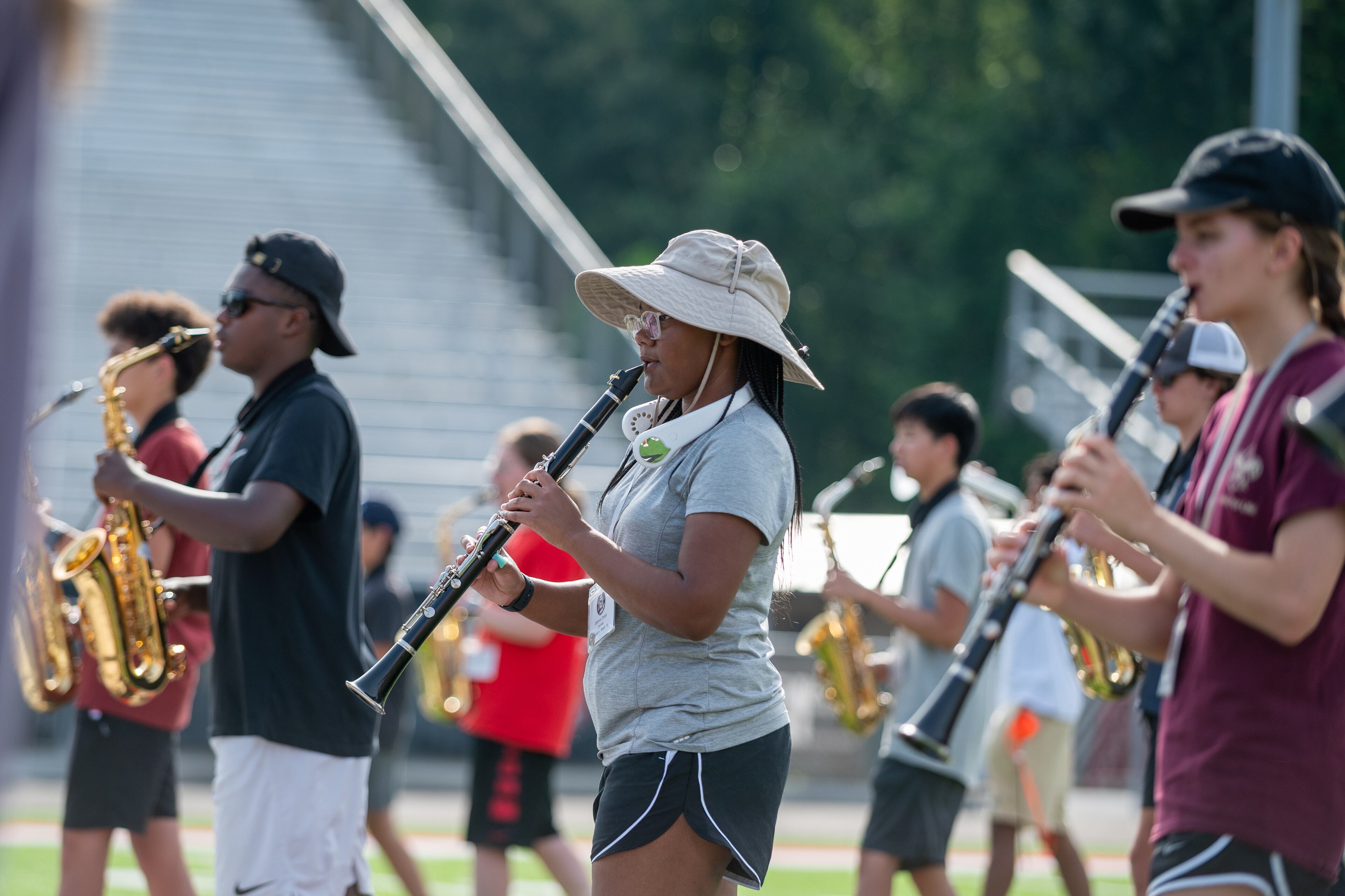 Some members of the North Gwinnett High School band take to neck fans and wide-brim hats to beat the heat during practice Wednesday, July 26, 2023. (Jamie Spaar for The Atlanta Journal-Constitution)