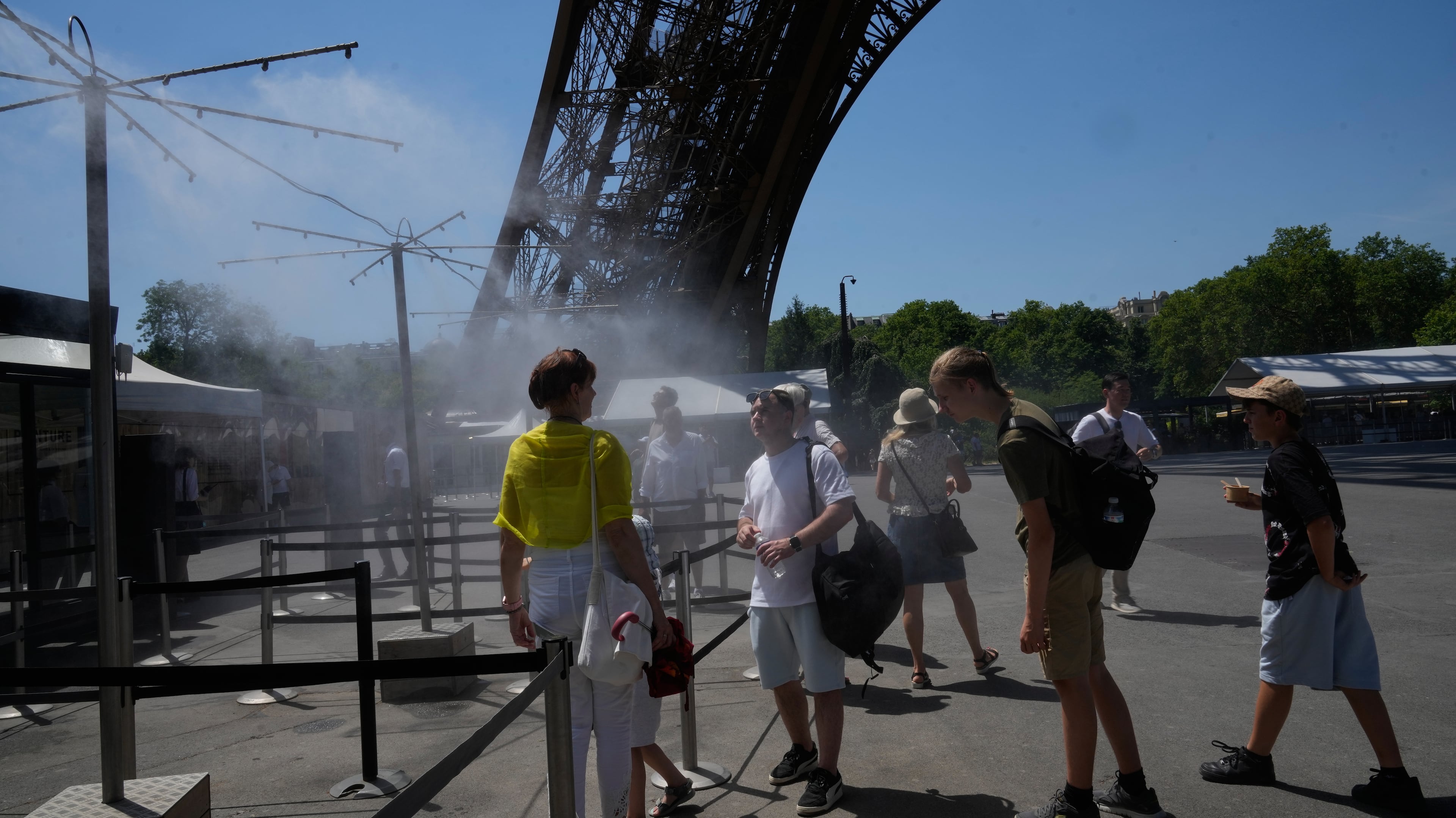 People cool off in a water spray at the Eiffel Tower in Paris, Sunday, June 21, 2026. (AP Photo/Michel Euler)