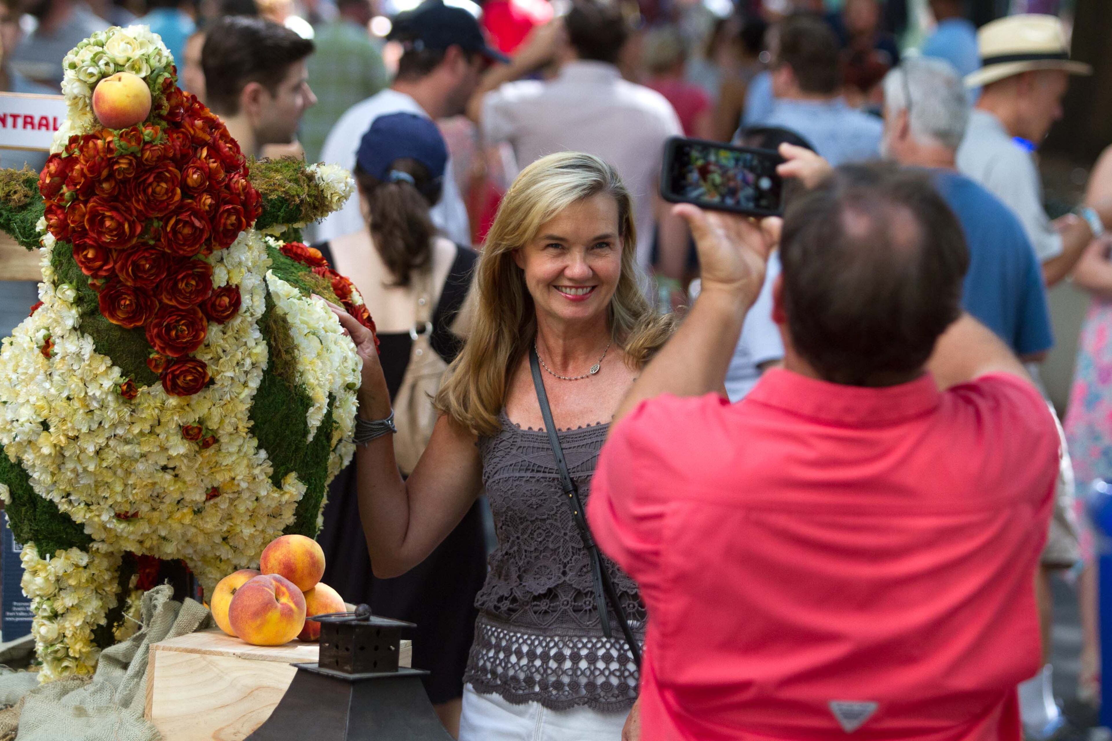 Amy Dresser gets her photograph taken by a sculpture of a pig during the PeachFest in Atlanta Ga Sunday, July 29, 2018. PeachFest a non-profit festival, returned to downtown Atlanta for its second year. STEVE SCHAEFER / SPECIAL TO THE AJC