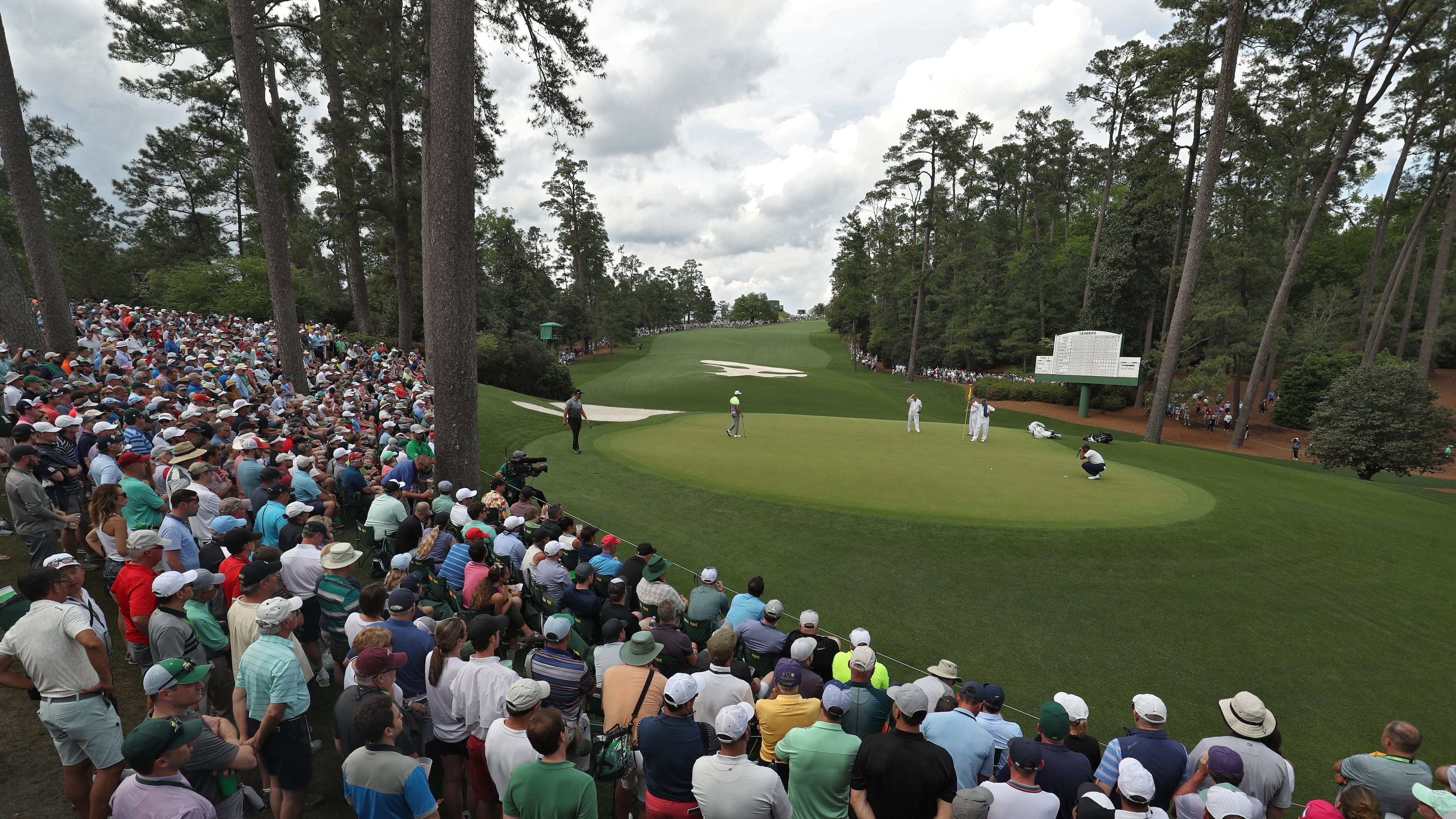 A huge gallery congregates around the green on 10 as Tiger Woods putts for a par Friday - a few actually got to see him. (Jason Getz / Special to the AJC)