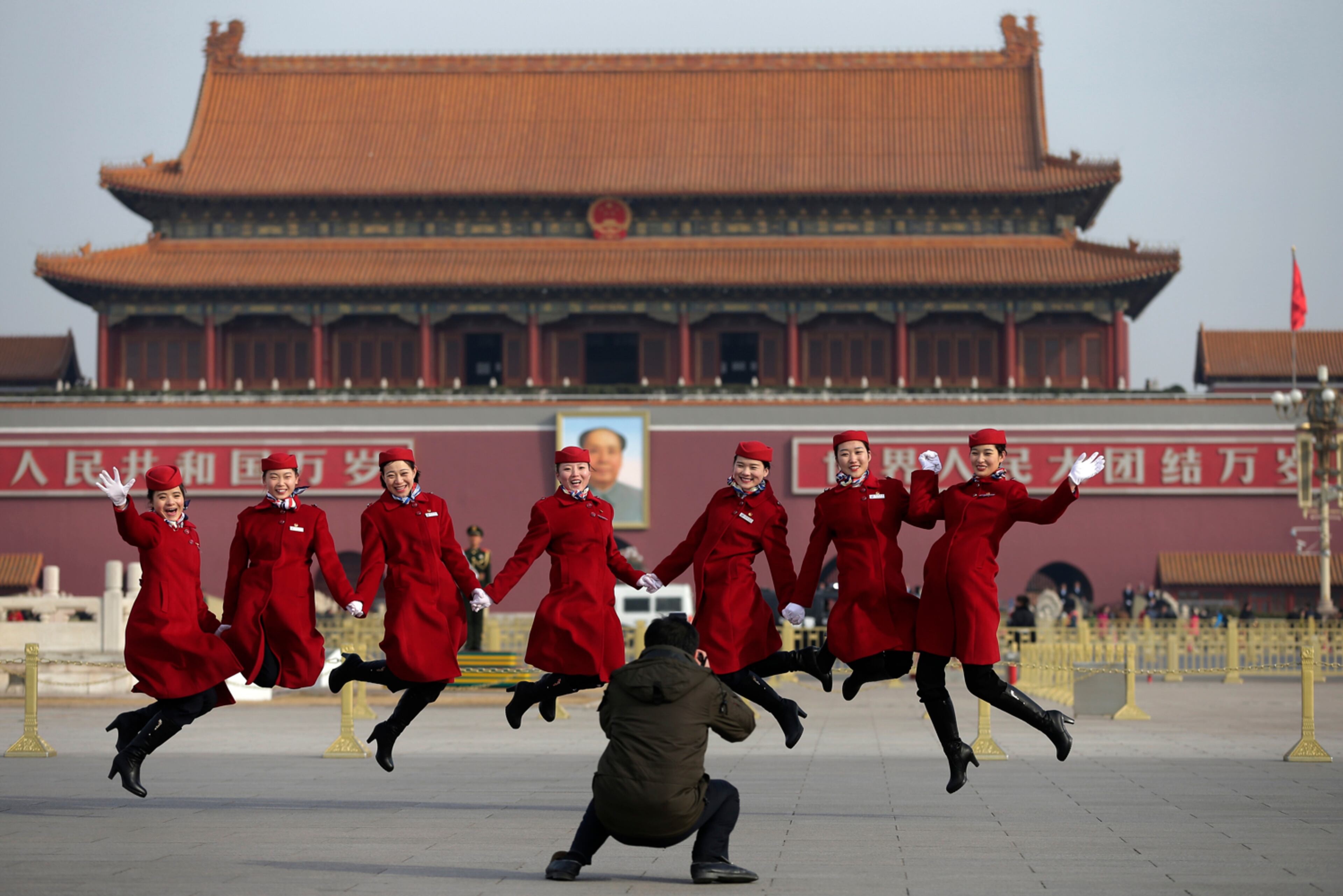 HOSTESSES TAKING FLIGHT--Chinese hostesses, who serve the delegates of the National People's Congress, jump as they pose for photographs on Tiananmen Square during a plenary session of the NPC held at the Great Hall of the People in Beijing Thursday, March 12, 2015. Thousands of delegates from across the country are in the Chinese capital to attend the annual National People's Congress and the Chinese People's Political Consultative Conference. (AP Photo/Andy Wong)