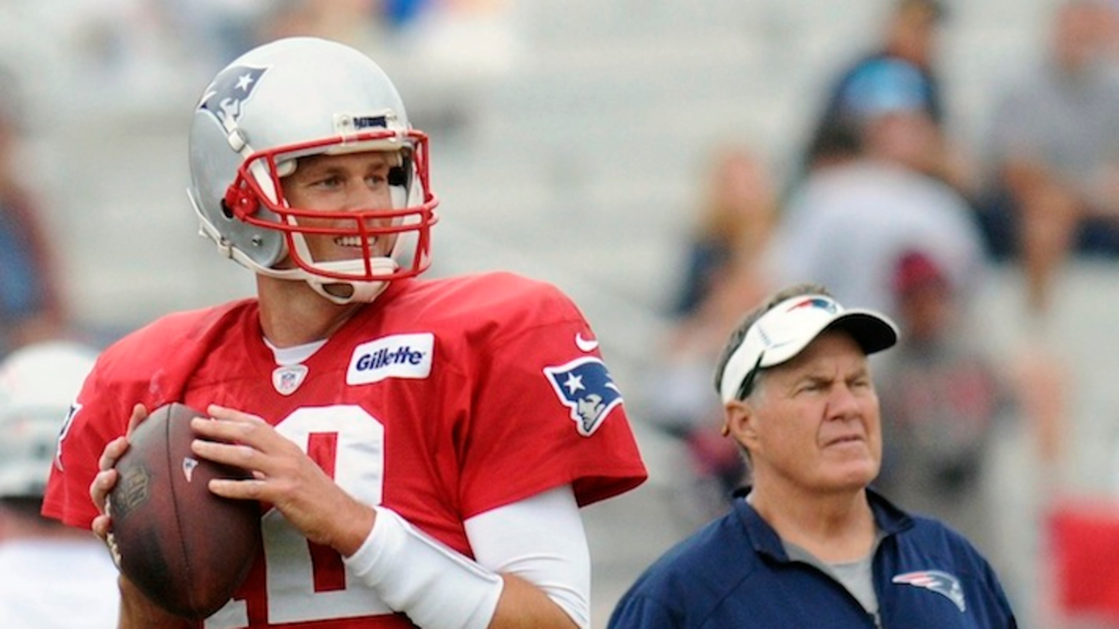 New England Patriots (12) quarterback Tom Brady smiles as he looks to pass as head coach Bill Belichick looks on during a joint practice with the two NFL football Houston Texans in White Sulphur Springs, W.Va. (AP Photo/Chris Jackson)