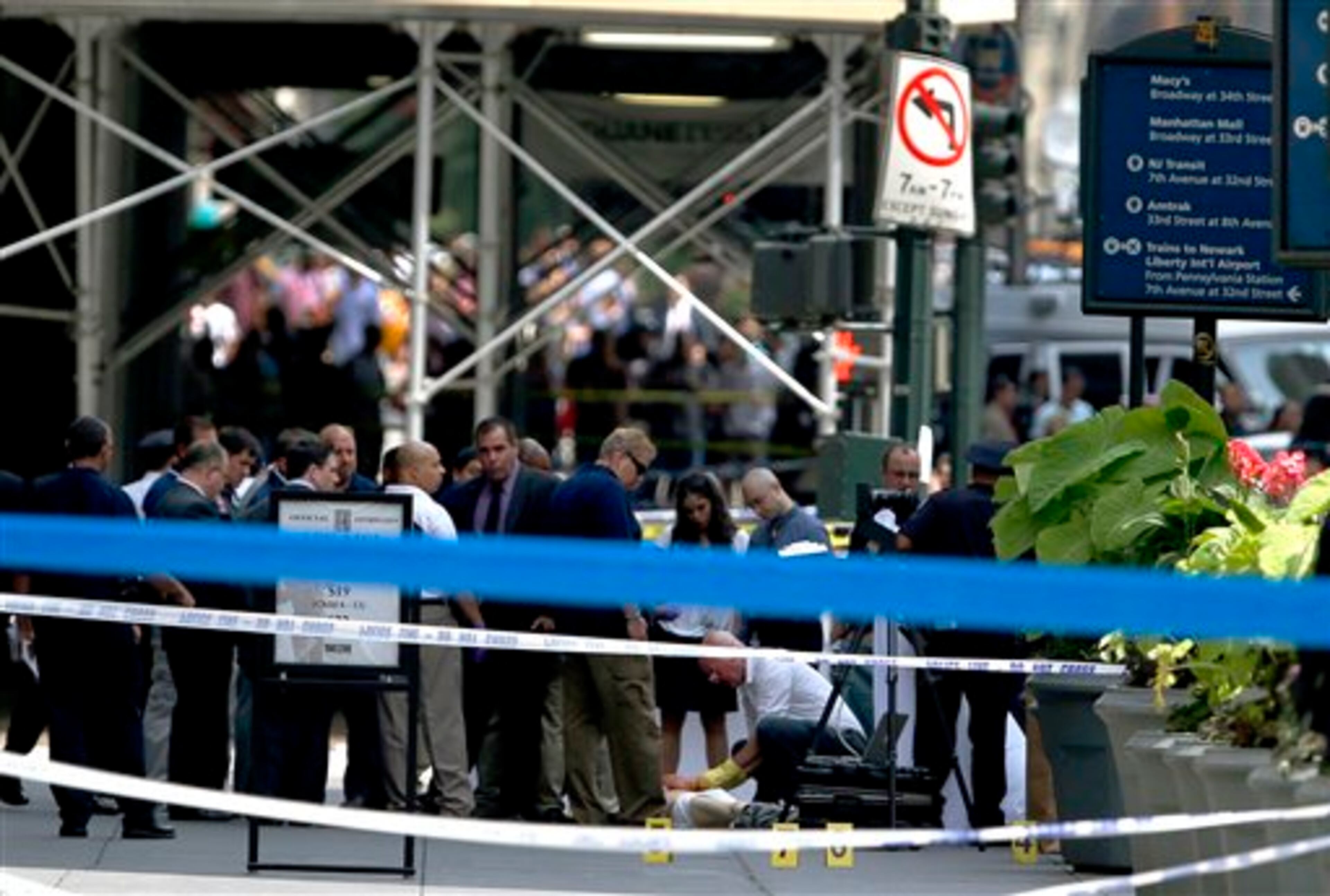 Officials examine the body of the shooter near the Empire State Building, Friday, Aug. 24, 2012, in New York. Police say Jeffrey Johnson, 58, a recently laid-off worker, shot a former colleague to death near the iconic skyscraper and then randomly opened fire on people nearby before firing on police. New York City Mayor Michael Bloomberg said some of the victims may have been hit by police bullets as police and the gunman exchanged fire. (AP Photo/Julio Cortez)