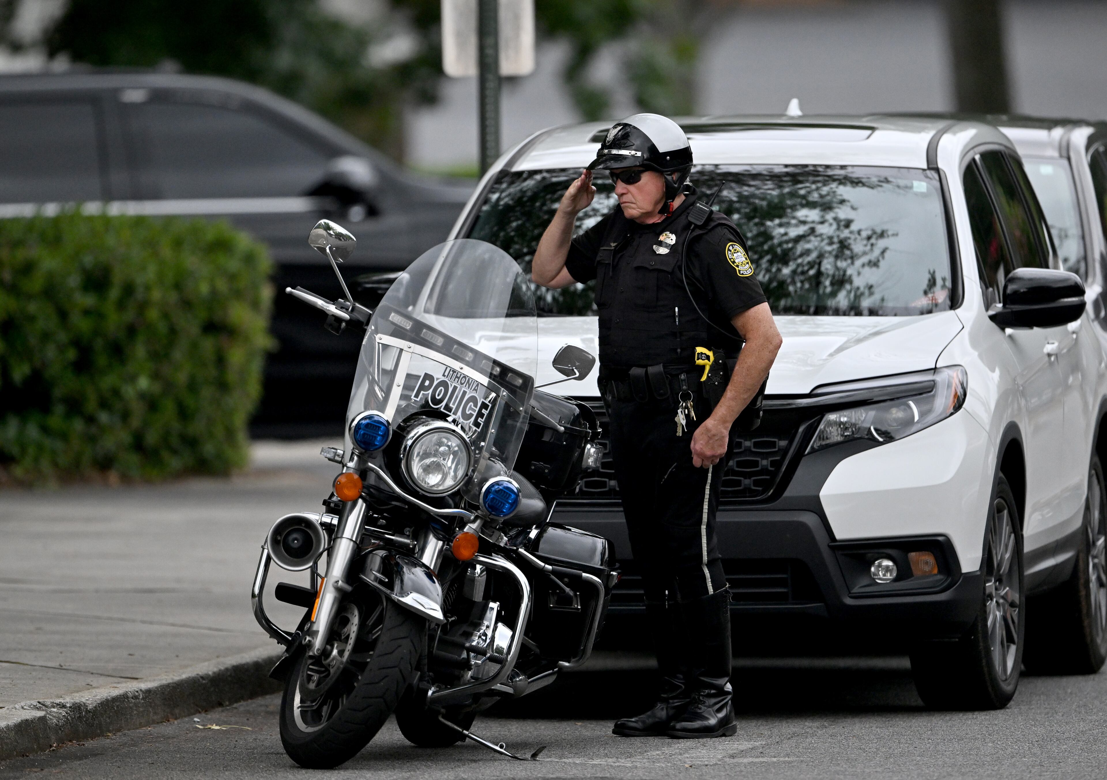 An office salutes before the memorial service for DeKalb County police Officer David Rose, who was killed while responding to the Aug. 8 shooting at the CDC. (Hyosub Shin/AJC)