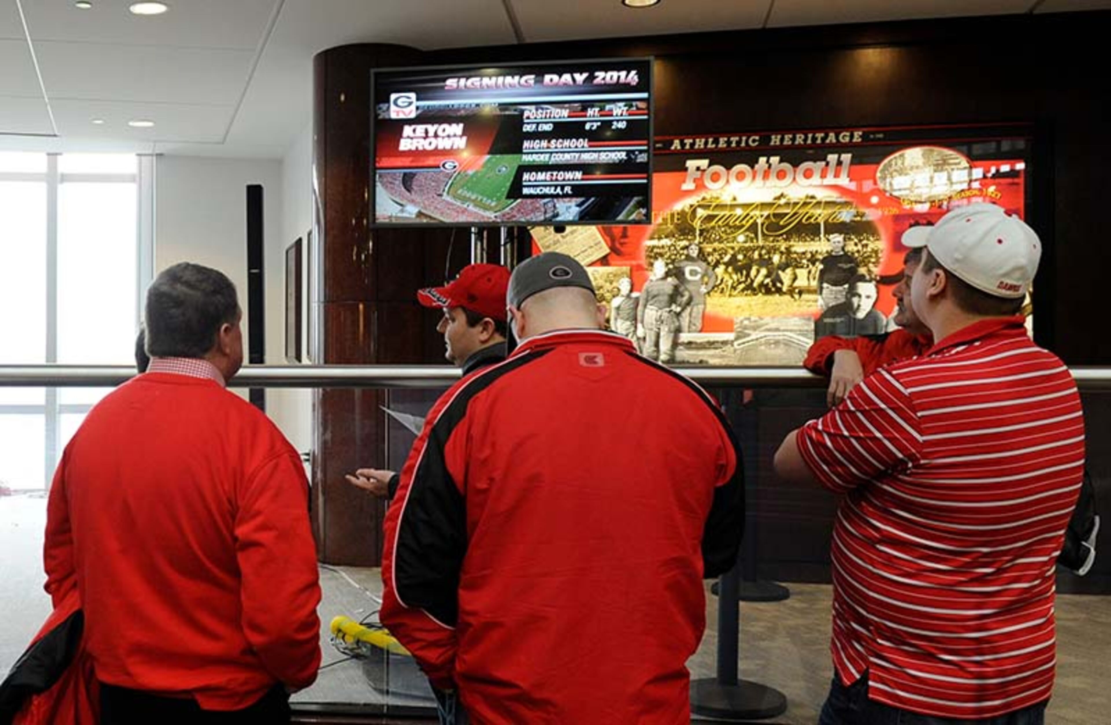 Fans keep their eyes on the screen for updates while awaiting for coach Mark Richt to address the gathered football enthusiasts at Butts-Mehre Complex during National Signgin Day Wednesday in Athens.