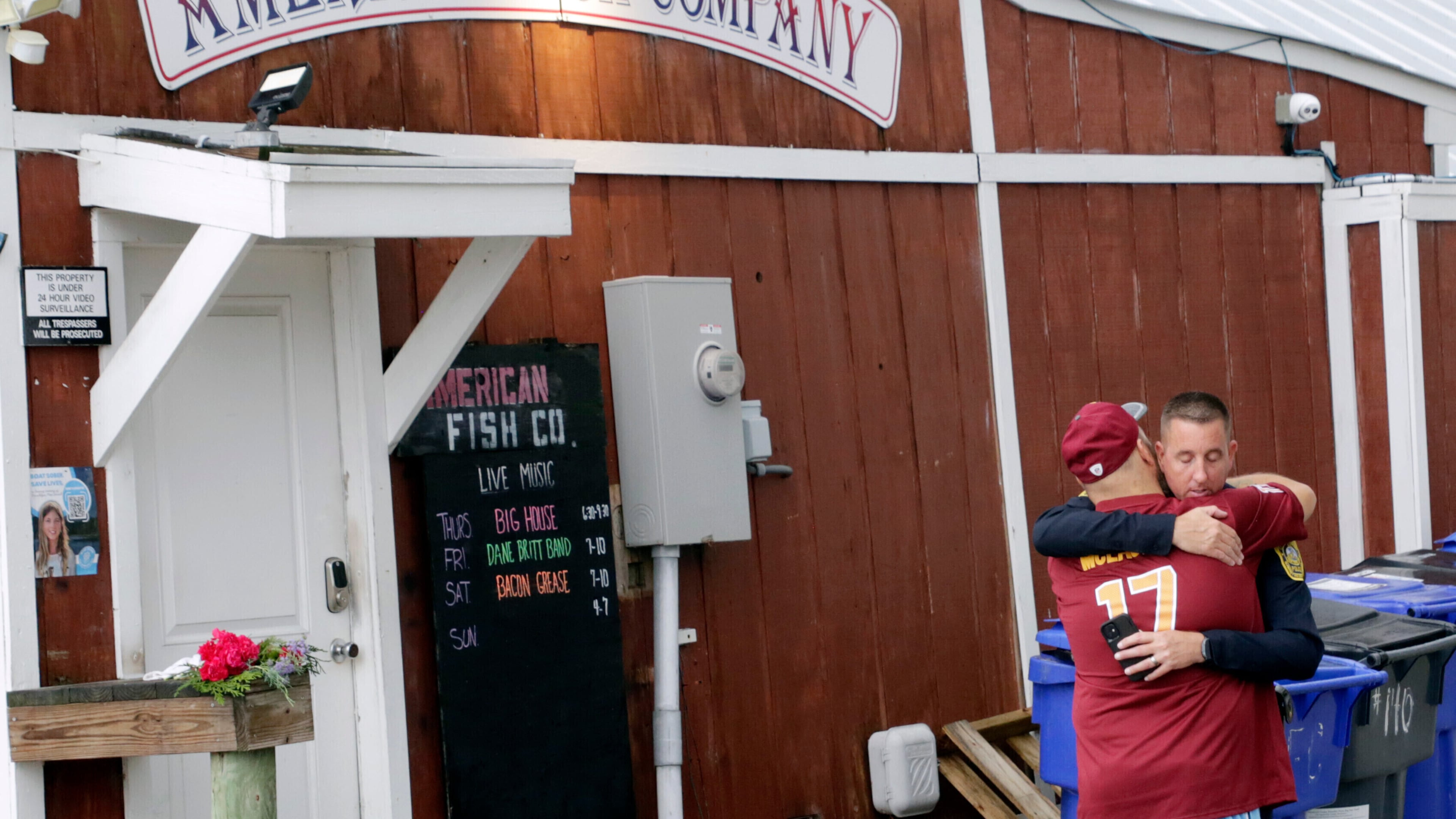 FILE - A man hugs a police officer in front of the American Fish Company following a fatal shooting that occurred the night before, Sept. 28, 2025, in Southport, N.C. (AP Photo/Chris Seward, File)