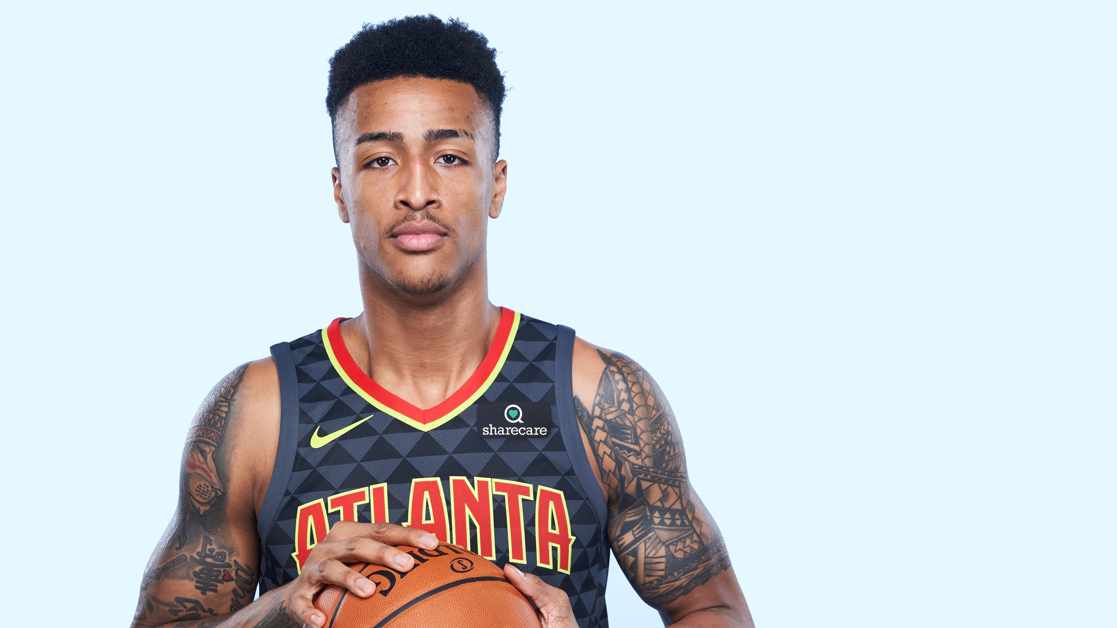Hawks rookie John Collins models new team jerseys with Sharecare sponsorship.