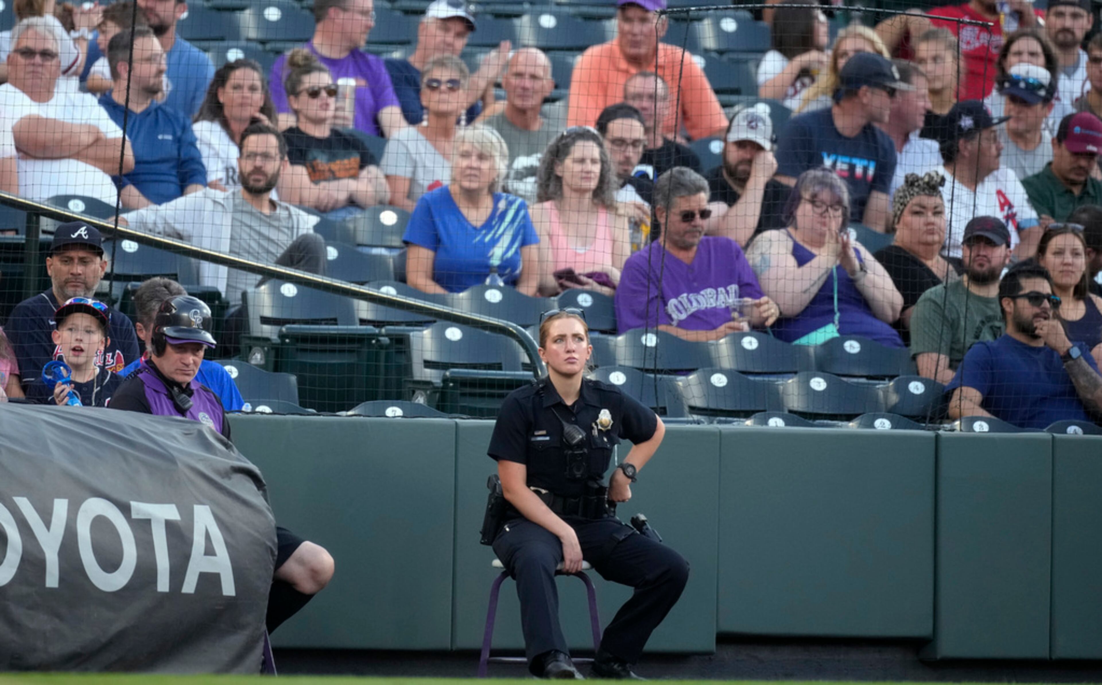 A Denver Police Department officer sits on the field near the stands of Coors Field during a game between the Braves and Colorado Rockies on Tuesday in Denver. Three spectators ran onto the field during a game Monday and two made contact with Braves star Ronald Acuna in right field. Tuesday night was uneventful and the Braves won the game 3-1. (AP Photo/David Zalubowski)