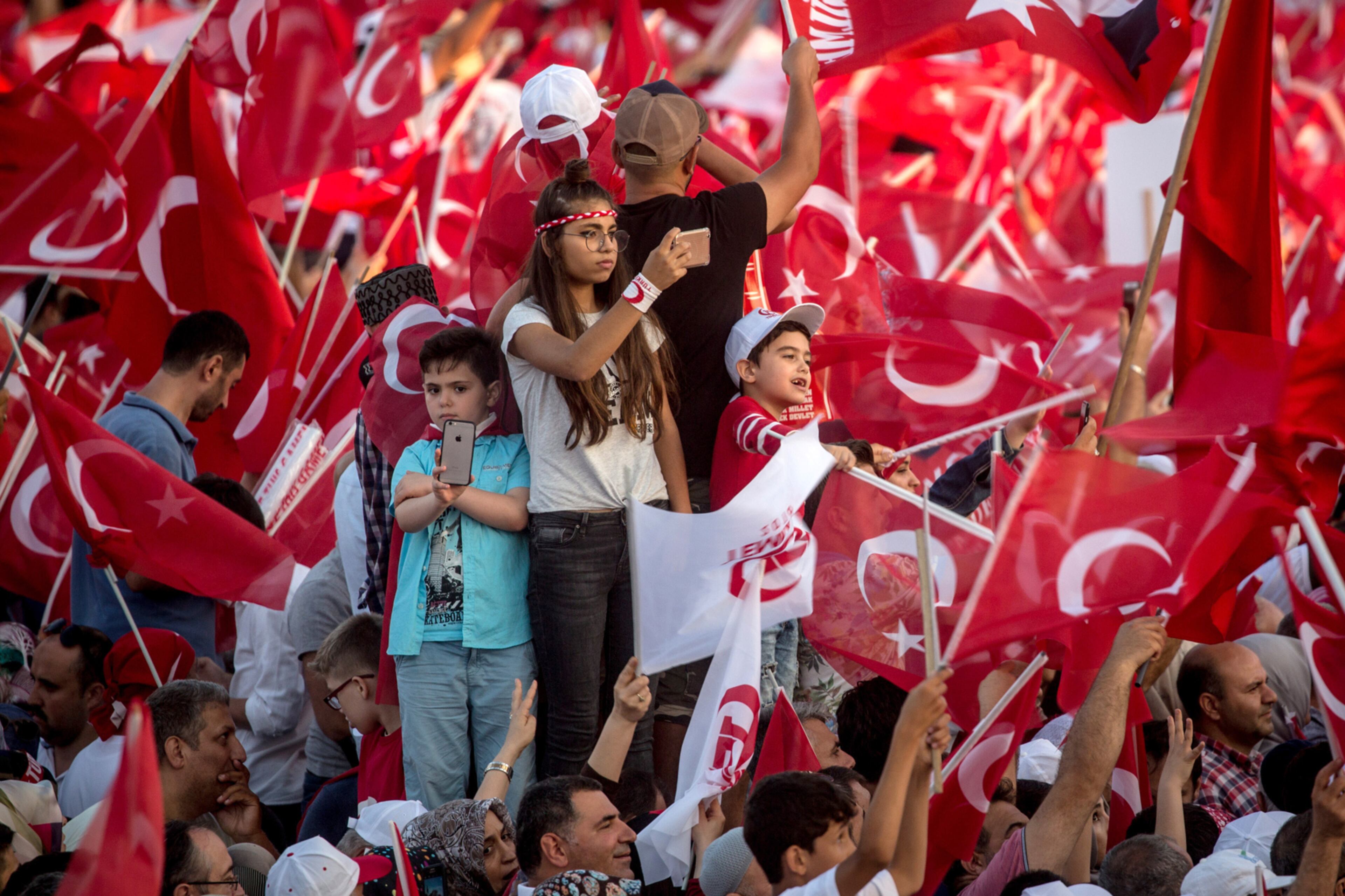 ISTANBUL, TURKEY - JULY 15: Children wave flags and take photographs of the crowd as they wait for official ceremonies to begin on the July 15 Martyrs Bridge on the first anniversary of the July 15, 2016 failed coup attempt on July 15, 2017 in Istanbul, Turkey. People gathered in public squares and at ceremonies across Turkey to mark the first anniversary of the failed coup attempt which saw 249 people die when military personnel attempted to overthrow the government and President Recep Tayyip Erdogan on the night of July 15, 2016. (Photo by Chris McGrath/Getty Images)