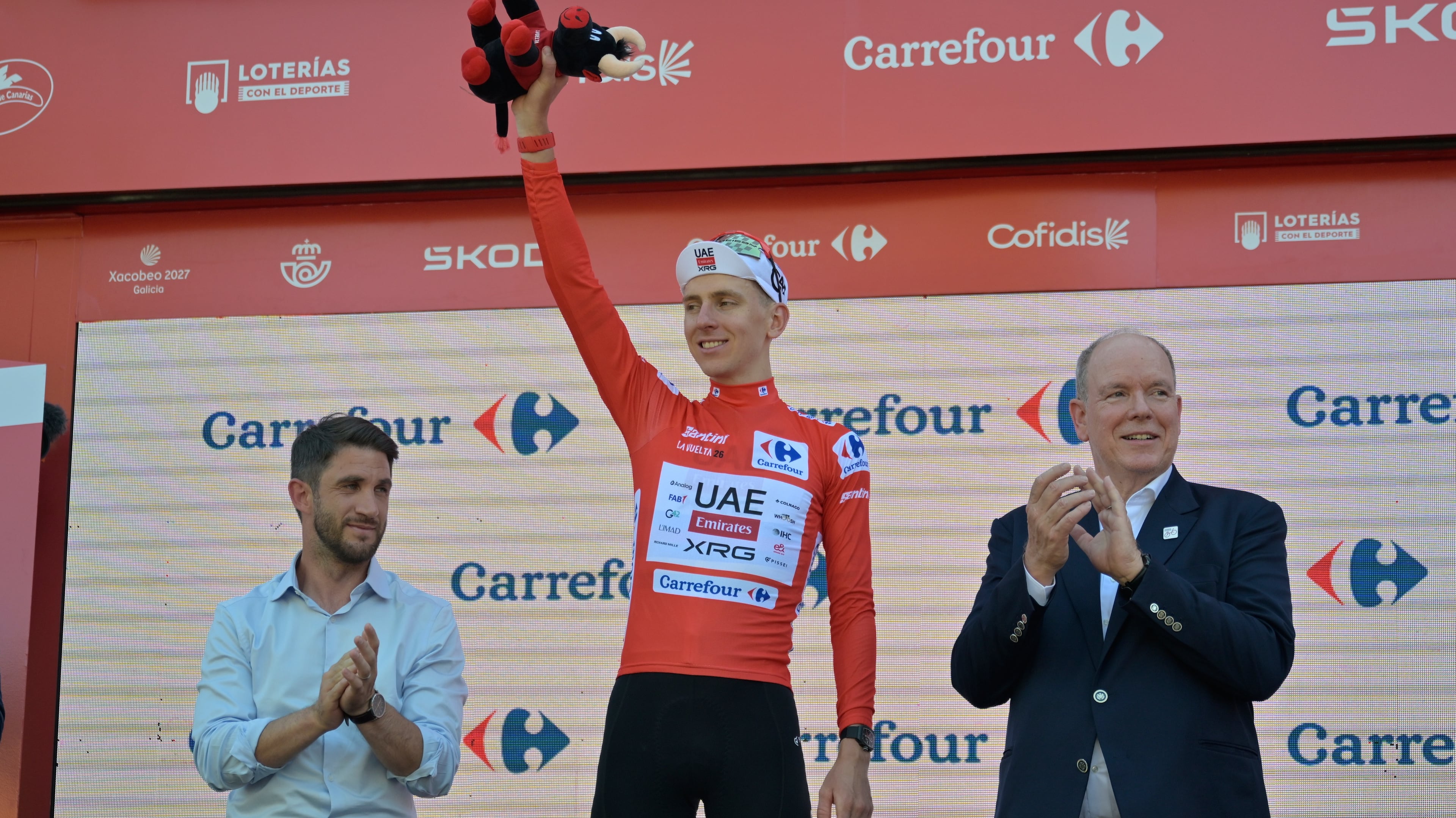 Slovenia's Tadej Pogacar, wearing the overall leader's red jersey celebrates on the podium after the second stage of the La Vuelta cycling race, with start in Monaco and finish in Manosque, France, Sunday, Aug. 23, 2026. (AP Photo/Philippe Magoni)