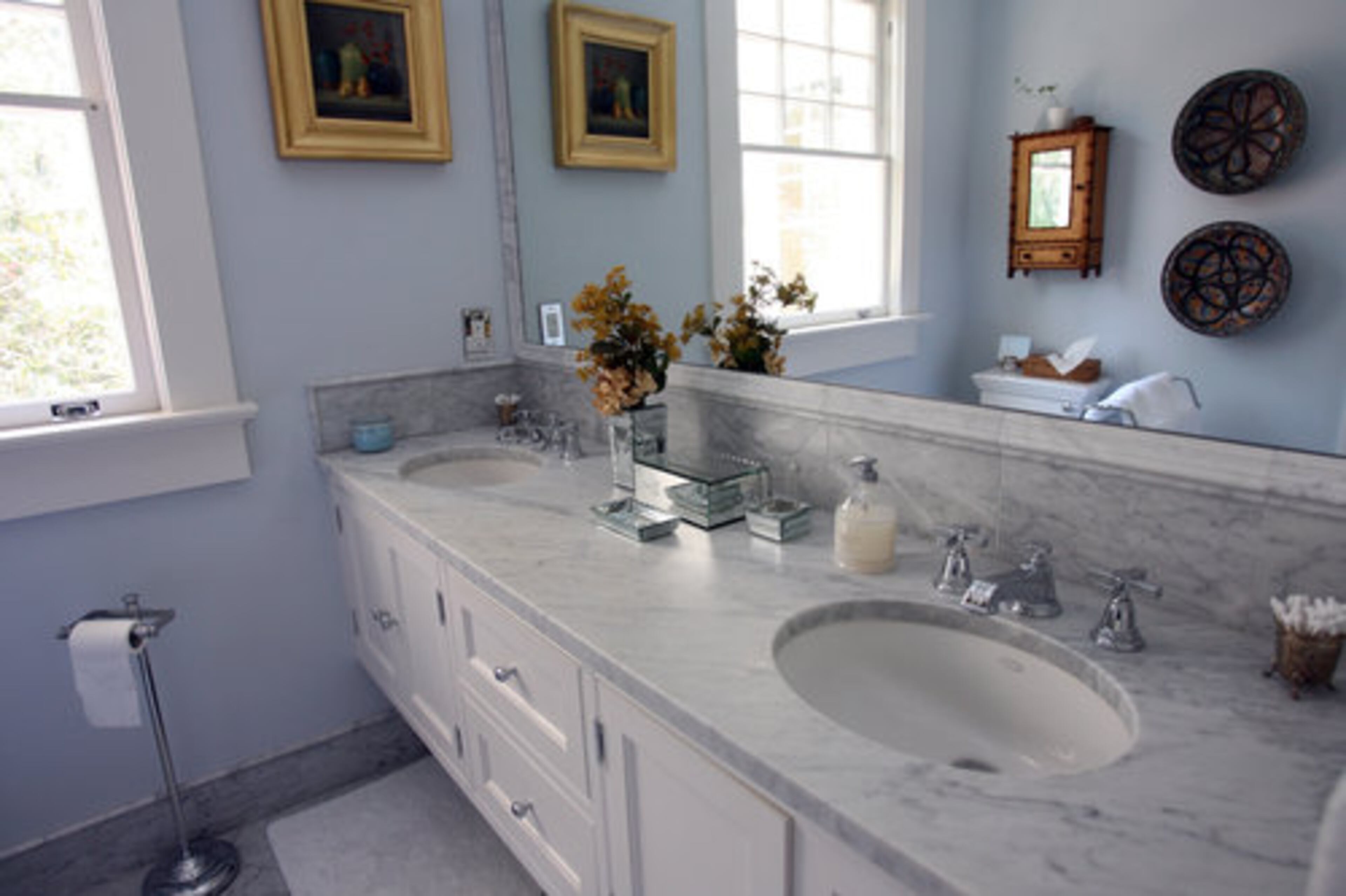 The master bathroom offers a double sink and several pieces of artwork.