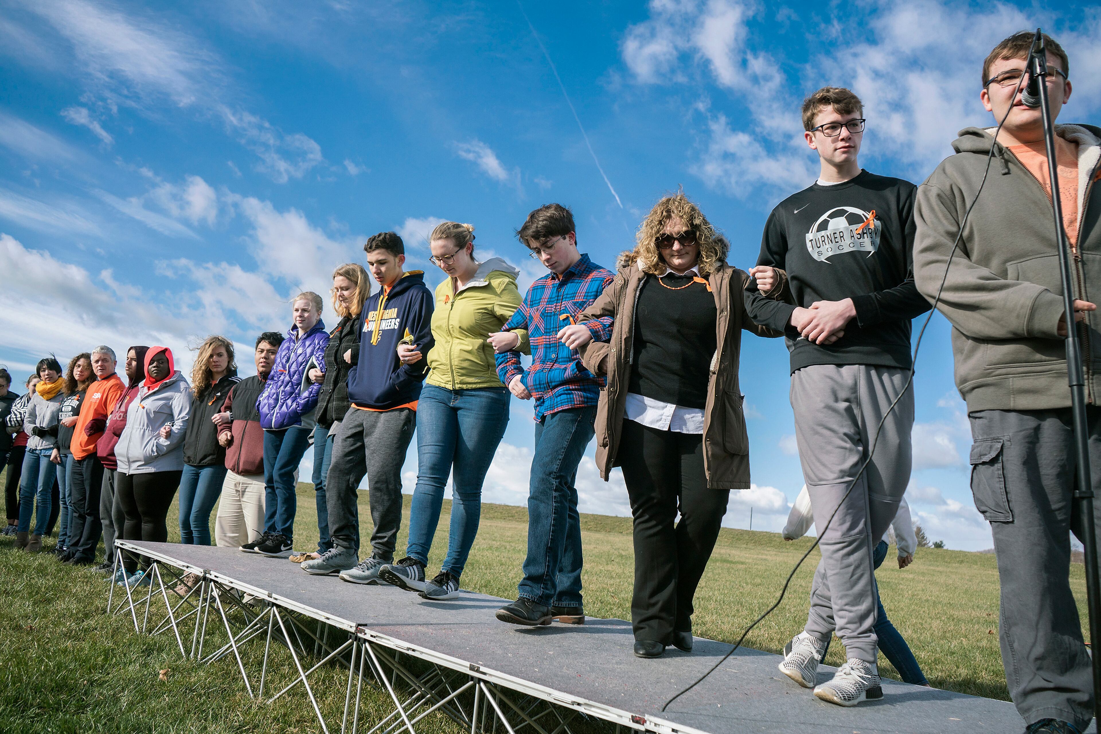 Turner Ashby High School junior Ian Phillips, right, 16, says Martin Duque Anguiano's name during a student-led walkout Wednesday, March 14, 2018, in Bridgewater, Va., as part of the national walkout to honor the victims of last month's shooting at Marjory Stoneman Douglas High School in Parkland, Fla. (Nikki Fox/Daily News-Record via AP)
