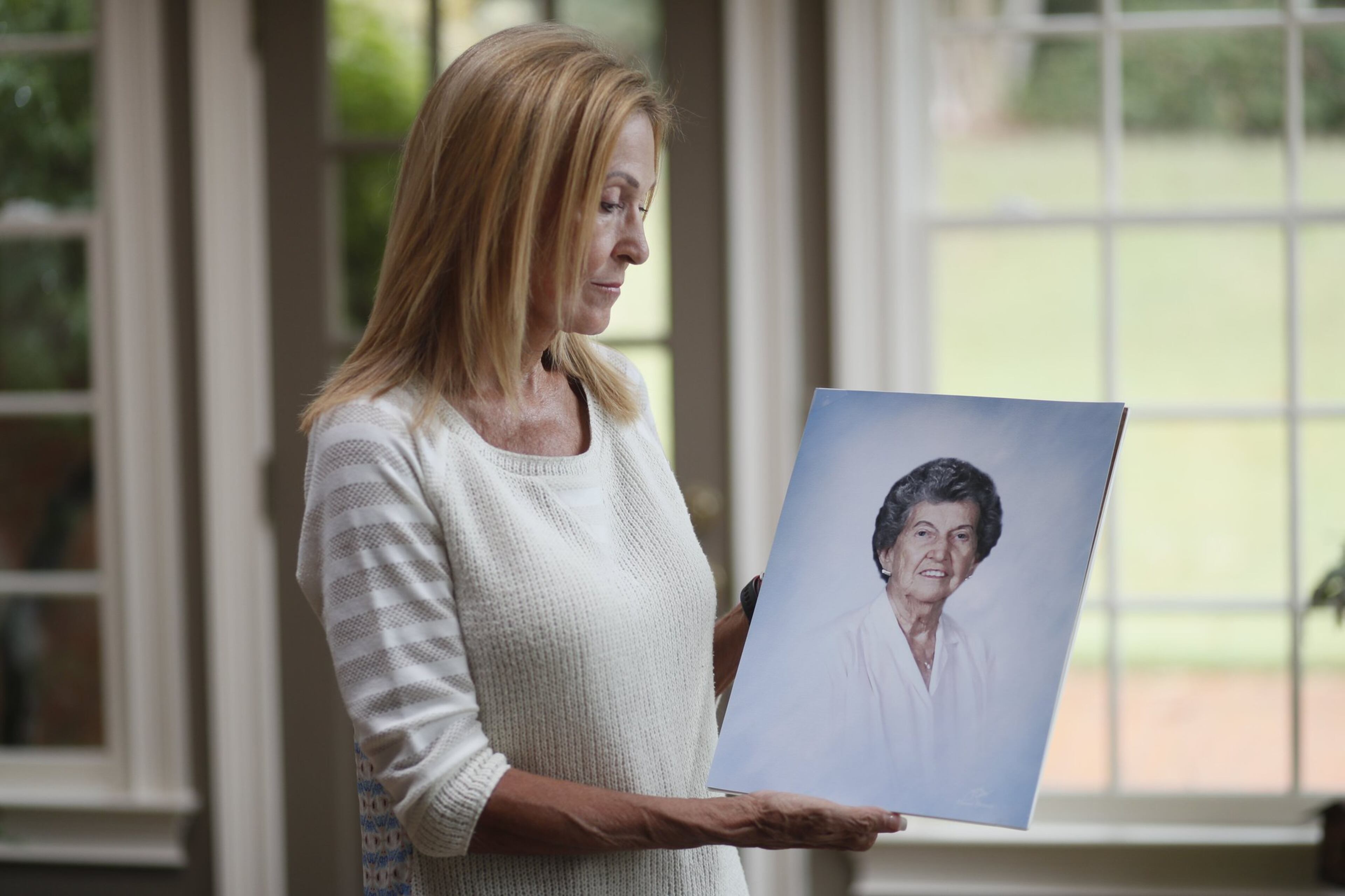 Gail Walker shows a photo of her mother, Lucile McMichael Brown, who died in 2015 after wandering out of an assisted living facility in Macon one night. Brown, a widowed great-grandmother and retired teacher, took a violent fall down a steep hill and broke her neck. Bob Andres/ robert.andres@ajc.com