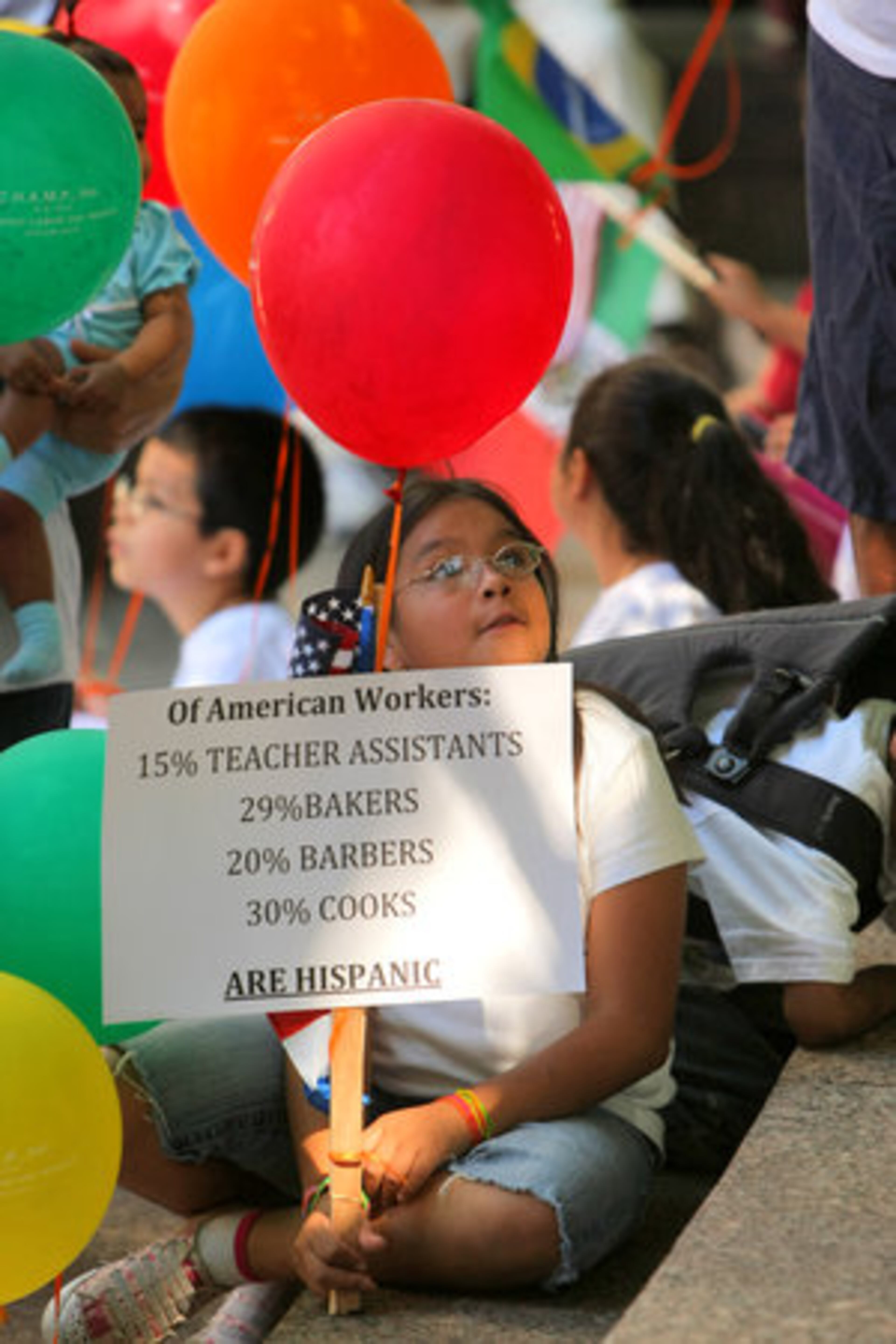 Sarai Chavira-10 of Alpharetta listens to the speakers at Woodruff Park Monday. Organizers of the parade and rally wanted emphasize the positive contributions of Hispanics to the state. Balloons, various Latin American flags and signs denoting facts and bullets about Hispanic workers and their contributions to the economic fabric of the US were held by participants.