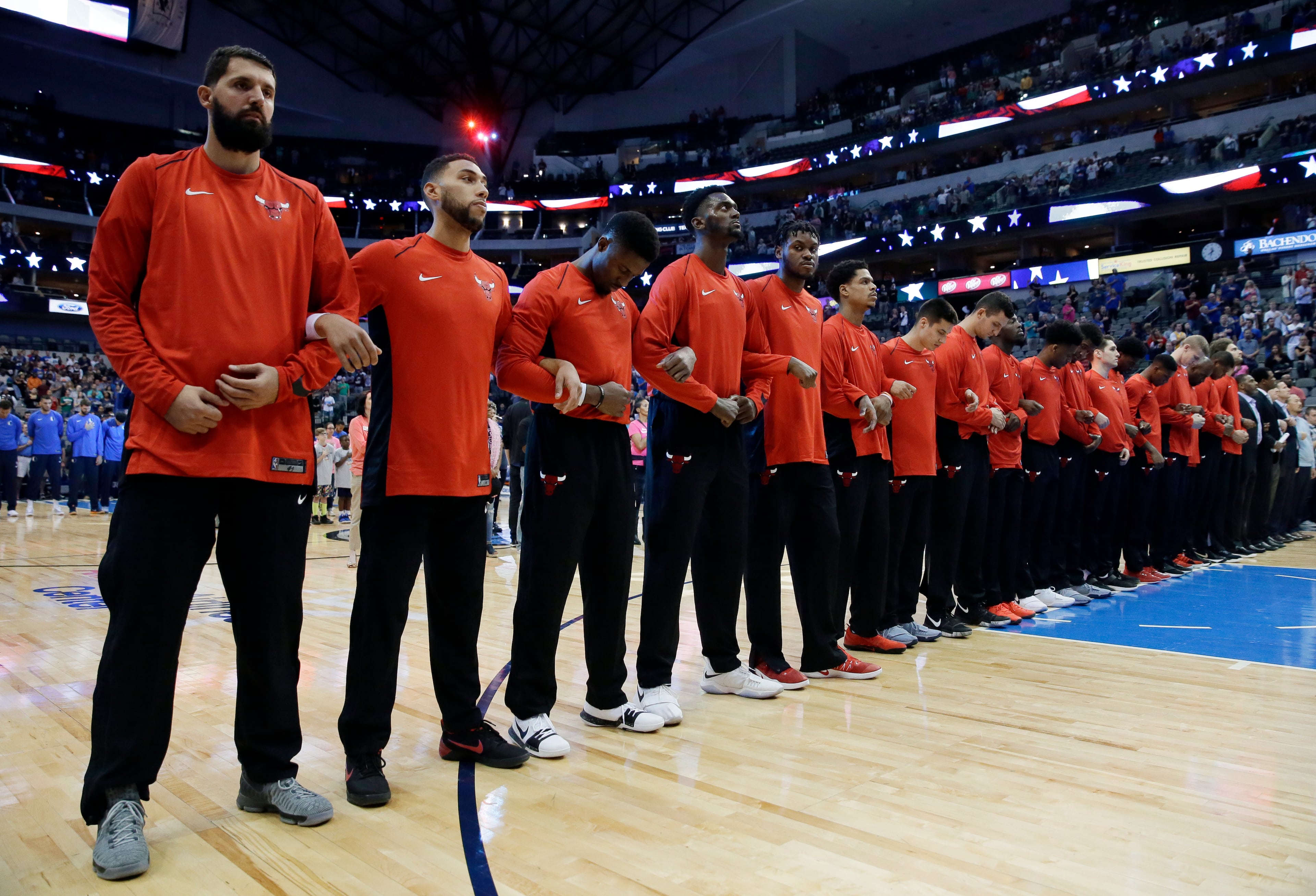 The Chicago Bulls interlock arms during the national anthem before the team's NBA basketball game against the Dallas Mavericks on Wednesday, Oct. 4.