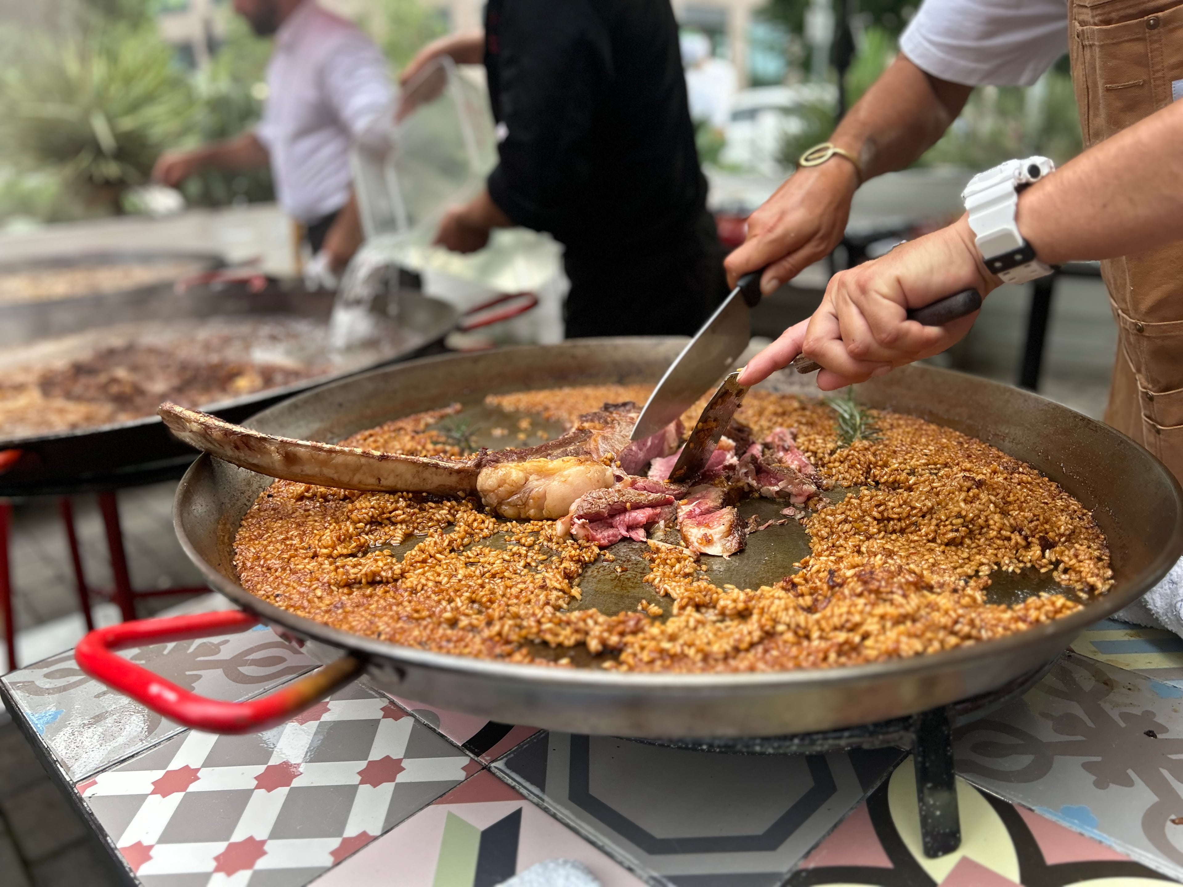 Edu Torres slices a tomahawk steak on top of a paella for a demonstration held at Buena Vida Tapas Bar. (Candy Hom for the AJC)