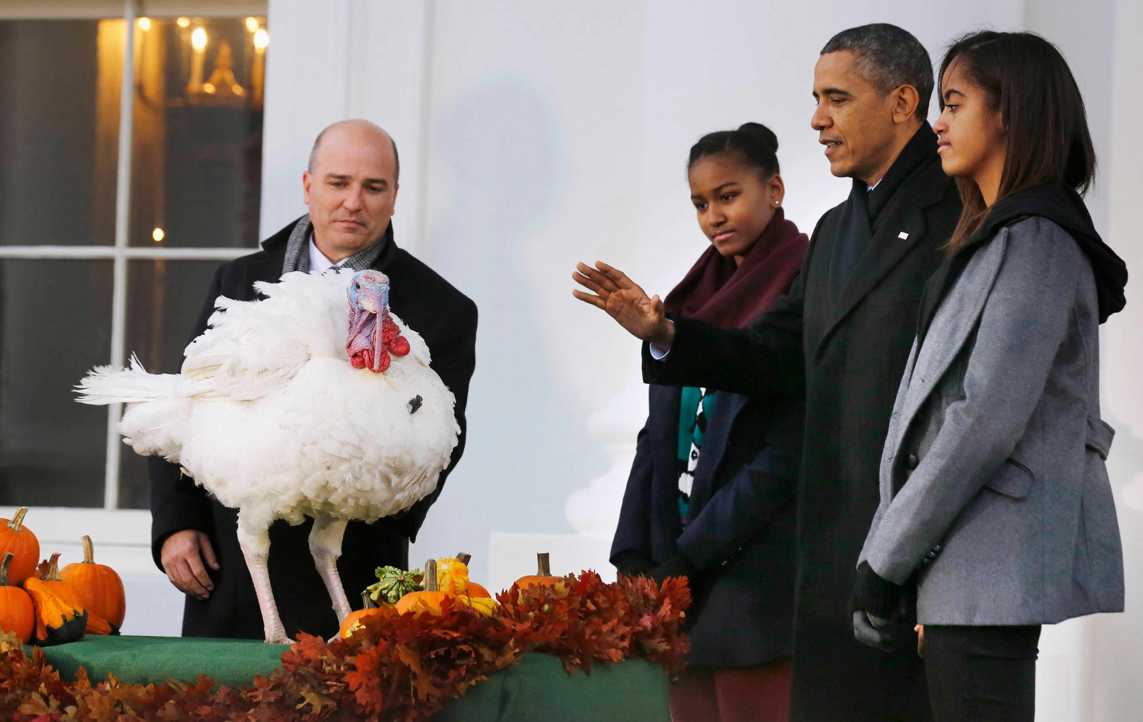 President Barack Obama joins his daughters Sasha (third right) and Malia (right) as they pardon National Thanksgiving Turkey Popcorn on the North Portico of the White House in Washington on Nov. 27, 2013. Chairman of the National Turkey Federation John Burkel looks on at left.