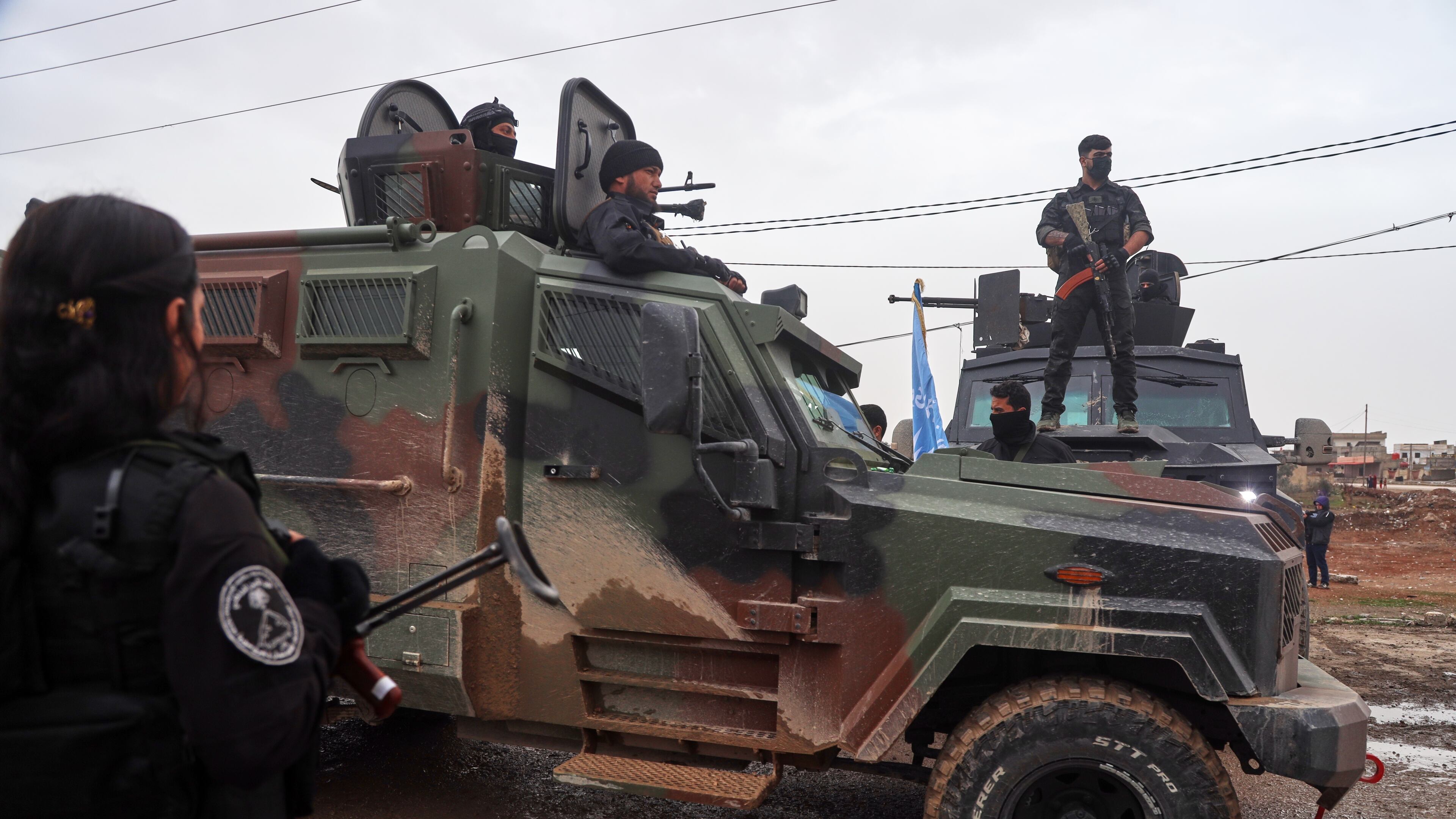 Kurdish-led Syrian Democratic Forces (SDF) soldiers, left and right, stand along the road as vehicles carrying a contingent of Syria's Interior Ministry security forces arrive to implement an agreement with the SDF aimed at stabilizing a ceasefire in al-Hassakeh, eastern Syria, Monday, Feb. 2, 2026. (AP Photo/Baderkhan Ahmad)