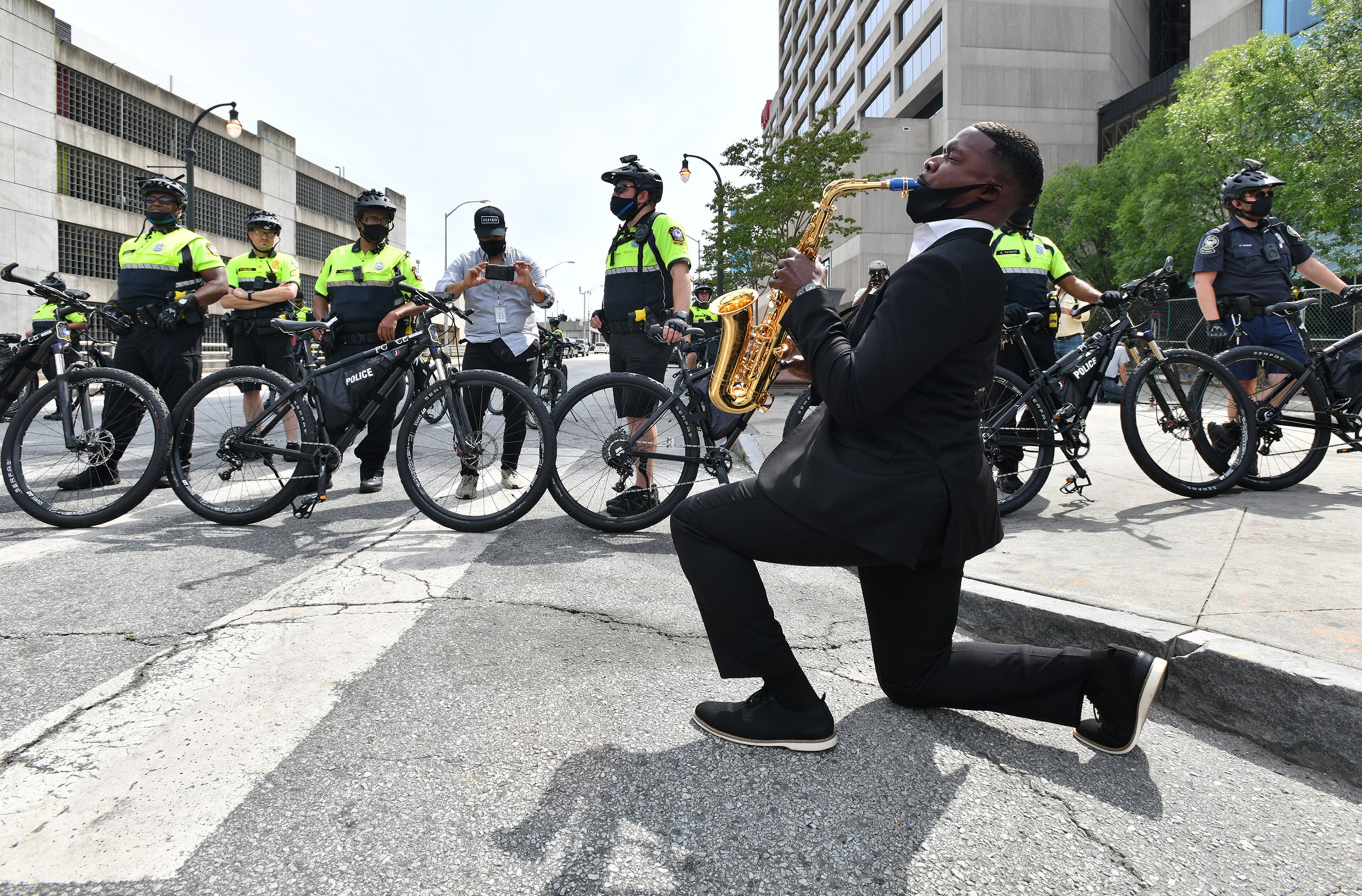 June 3, 2020 Atlanta - Jazz artist Richard Shaw, Jr. plays the saxophone as Atlanta Police bicycle unit blocking Marietta Street at Centennial Olympic Park Drive on Wednesday, June 3, 2020. Atlanta residents came together across the metro area Wednesday for the sixth consecutive day of protests against police brutality and racism. The curfew for the city of Atlanta was extended for the next five days, going into effect at 9 p.m. Wednesday. (Hyosub Shin / Hyosub.Shin@ajc.com)