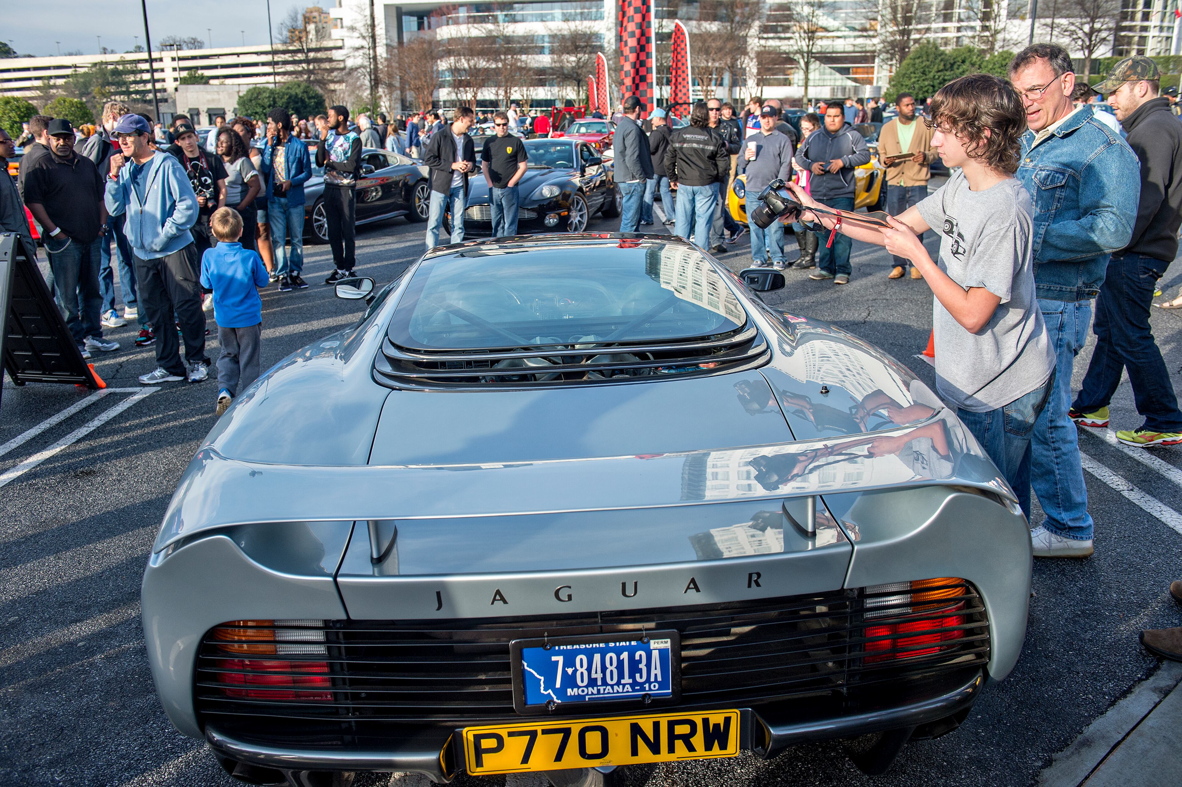 Ezra Evans (right) leans over a Jaguar XJ220 to take a photo of the engine compartment. JONATHAN PHILLIPS / SPECIAL