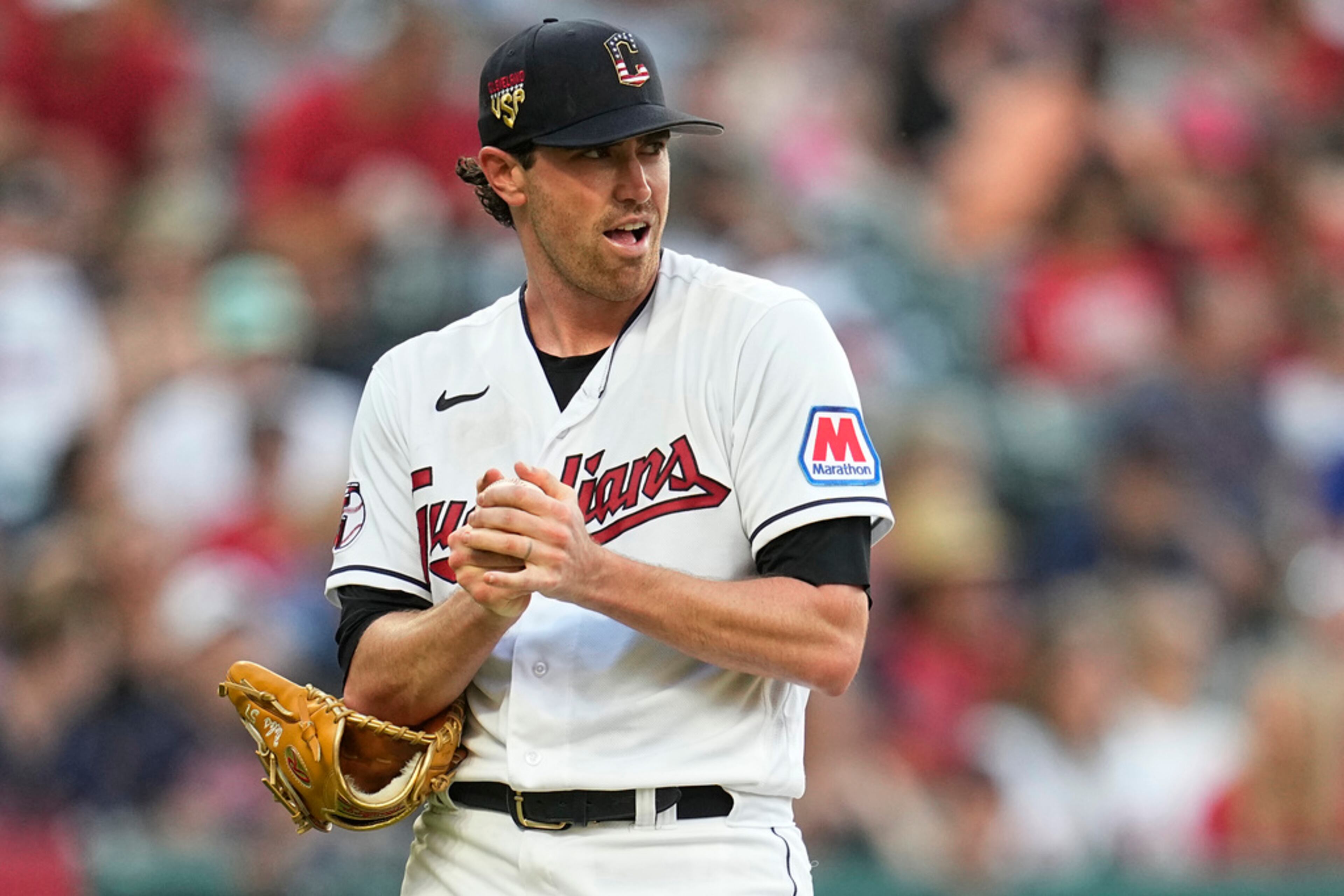 Cleveland Guardians starting pitcher Shane Bieber rubs up a new ball while Atlanta Braves' Ozzie Albies runs the bases on a home run during the fifth inning of a baseball game Tuesday, July 4, 2023, in Cleveland. (AP Photo/Sue Ogrocki)