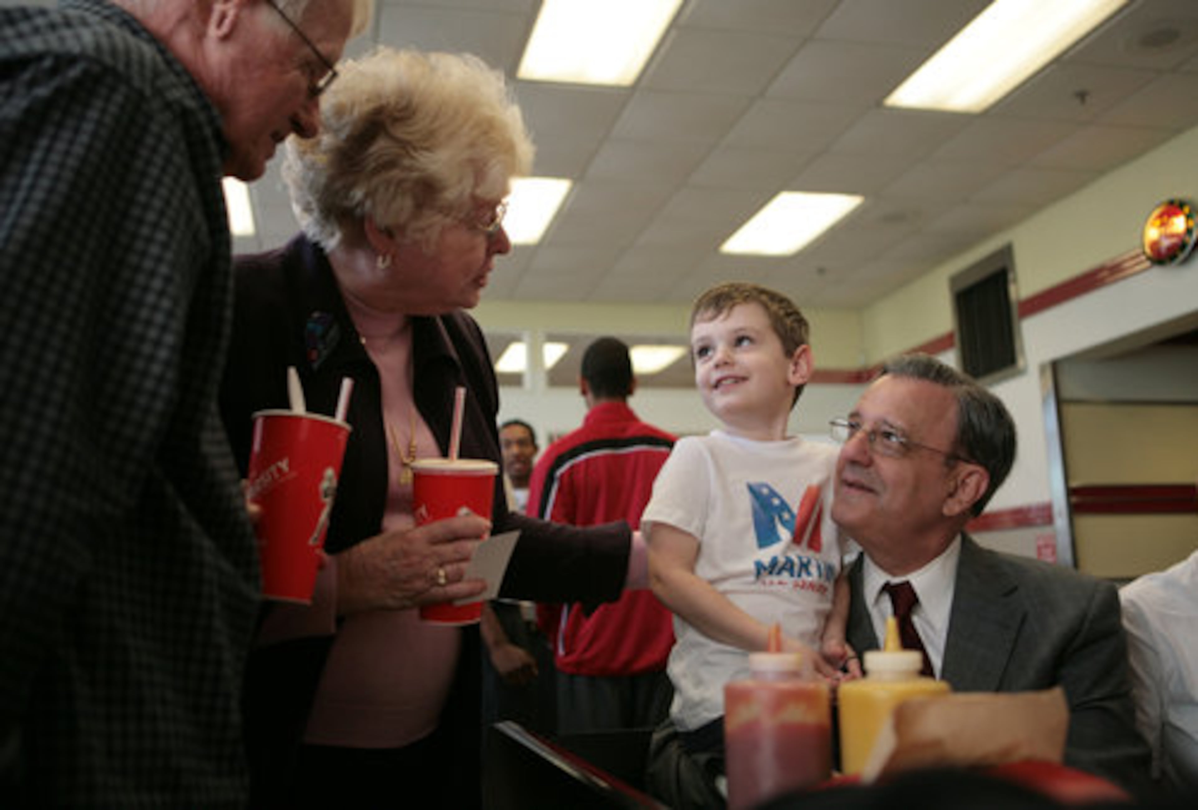 12:12 p.m. Atlanta: Holding his grandson Grant Walters, 3, Georgia Democratic Senate candidate Jim Martin (right) talks with supporters Joe (left) and Sue Bearden of Blueridge at the Varsity on Tuesday. Martin made appearances around town to get a few last minute votes.