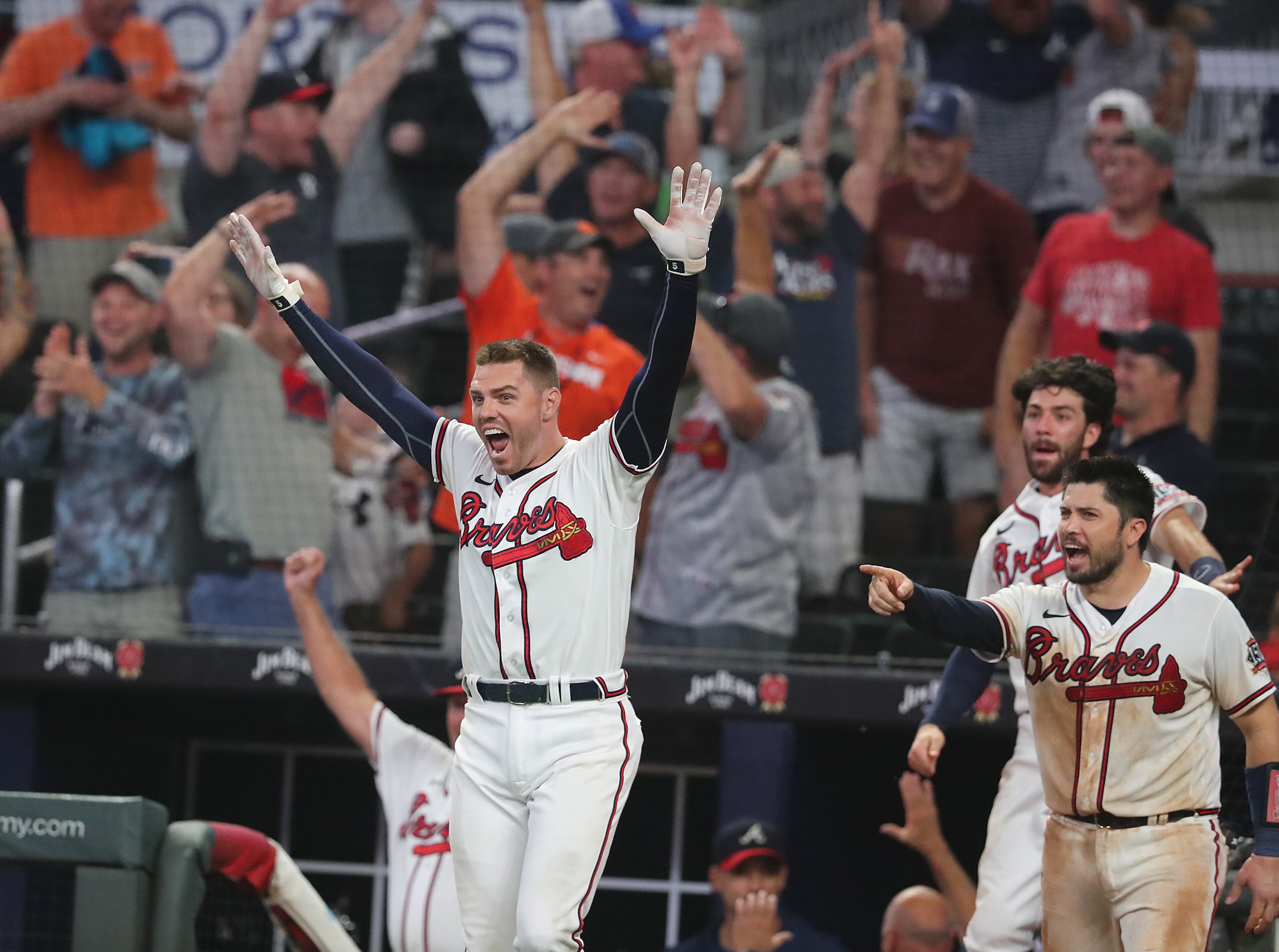 Atlanta Braves first baseman Freddie Freeman (left) and catcher Travis d'Arnaud react from the dugout as second baseman Ozzie Albies hits a 3-run walk-off homer for an 8-6 victory over the Cincinnati Reds during the 11th inning of a MLB baseball game on Wednesday, August 11, 2021, in Atlanta. “Curtis Compton / Curtis.Compton@ajc.com”