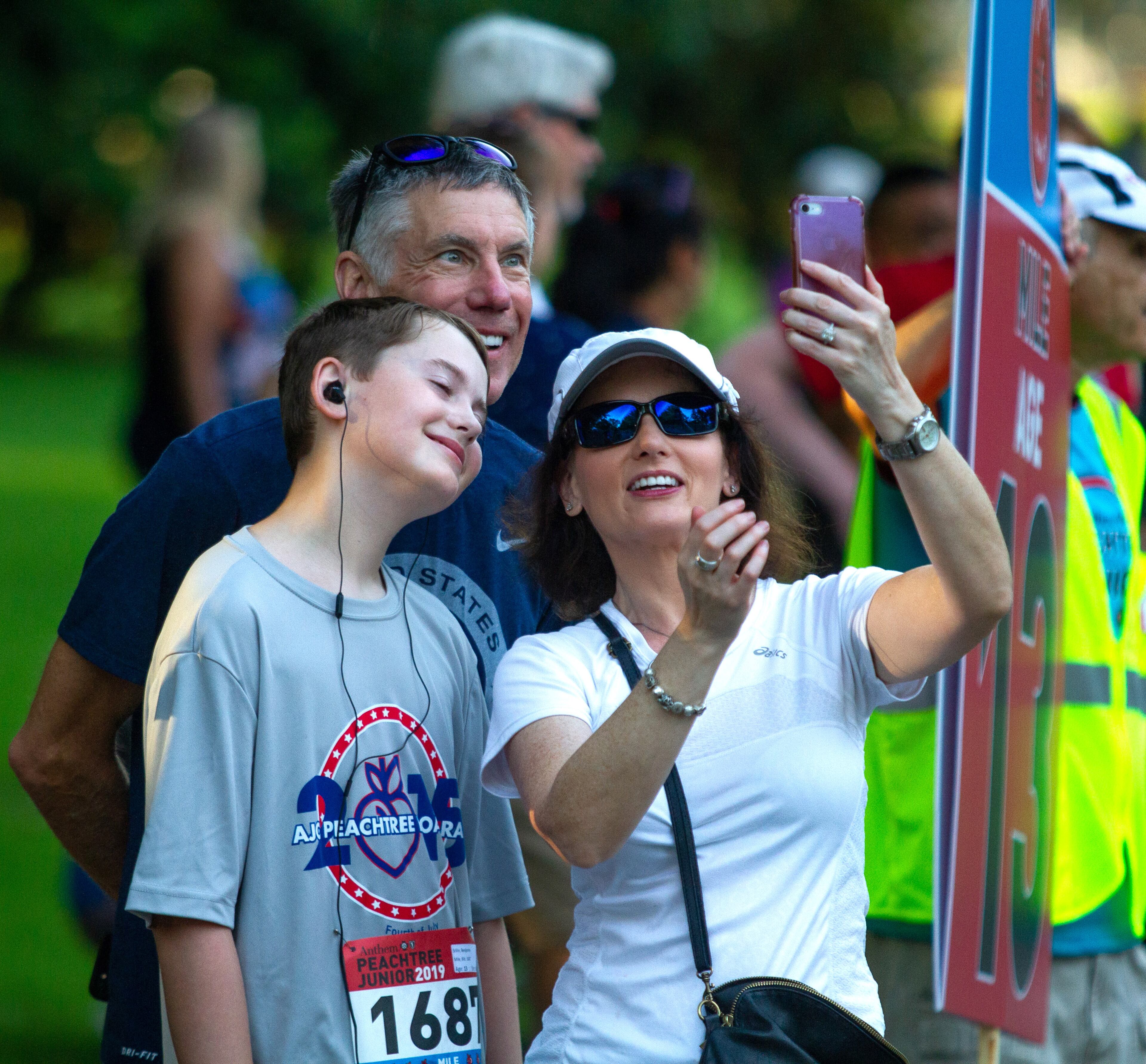 Wendy Lewis takes of photo with Benjamin Stilin (L) and Darren Lewis before the start of The Anthem Peachtree Junior race in Piedmont Park Wednesday, July 3, 2019. STEVE SCHAEFER / SPECIAL TO THE AJC