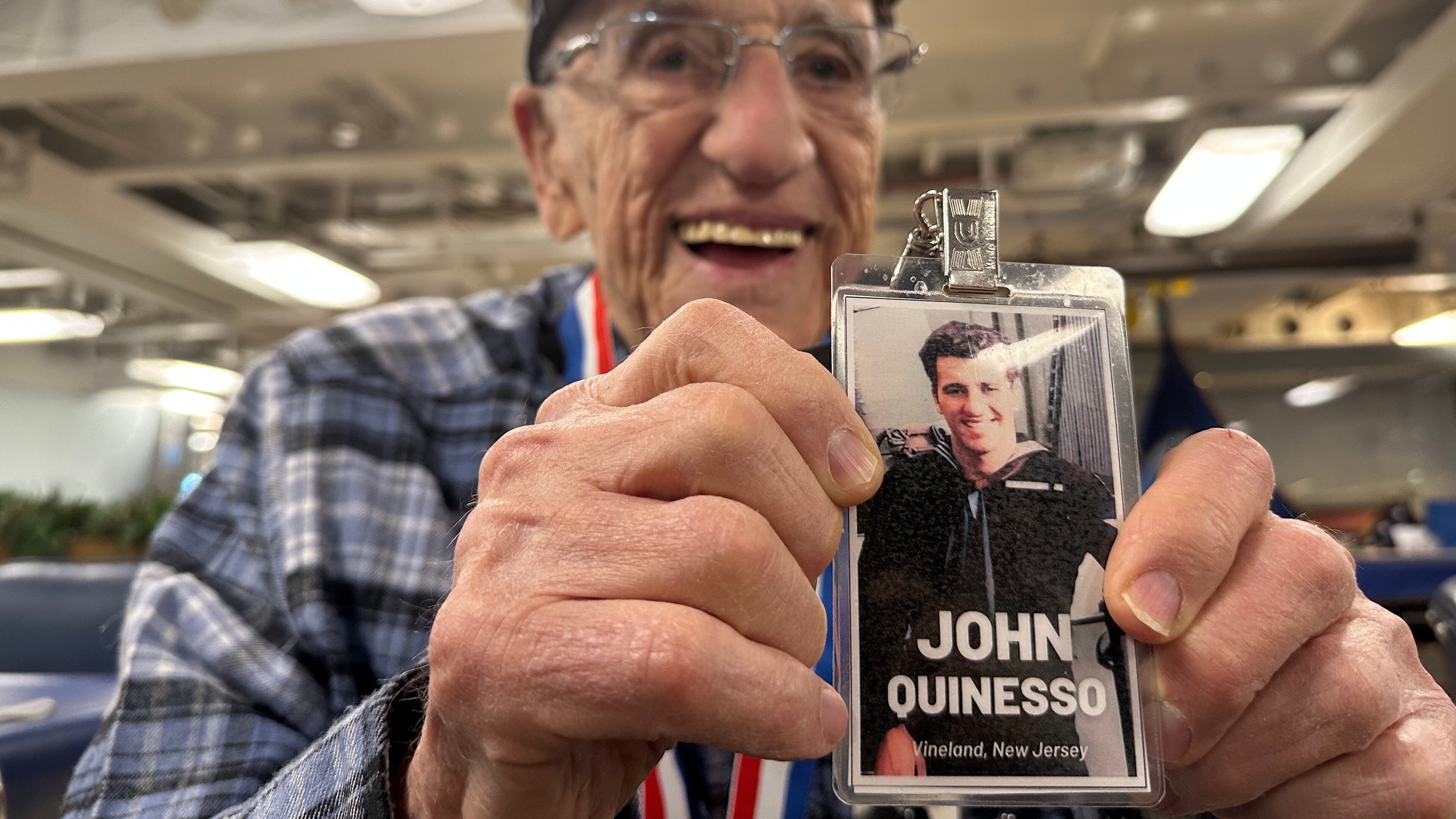 John "Johnny Q" Quinesso Sr, a WWII veteran, holds a photo of his younger self during his 100th birthday celebration on Thursday, Feb. 5, 2026 in Camden, N.J., aboard the Battleship New Jersey. (AP Photo/Tassanee Vejpongsa)