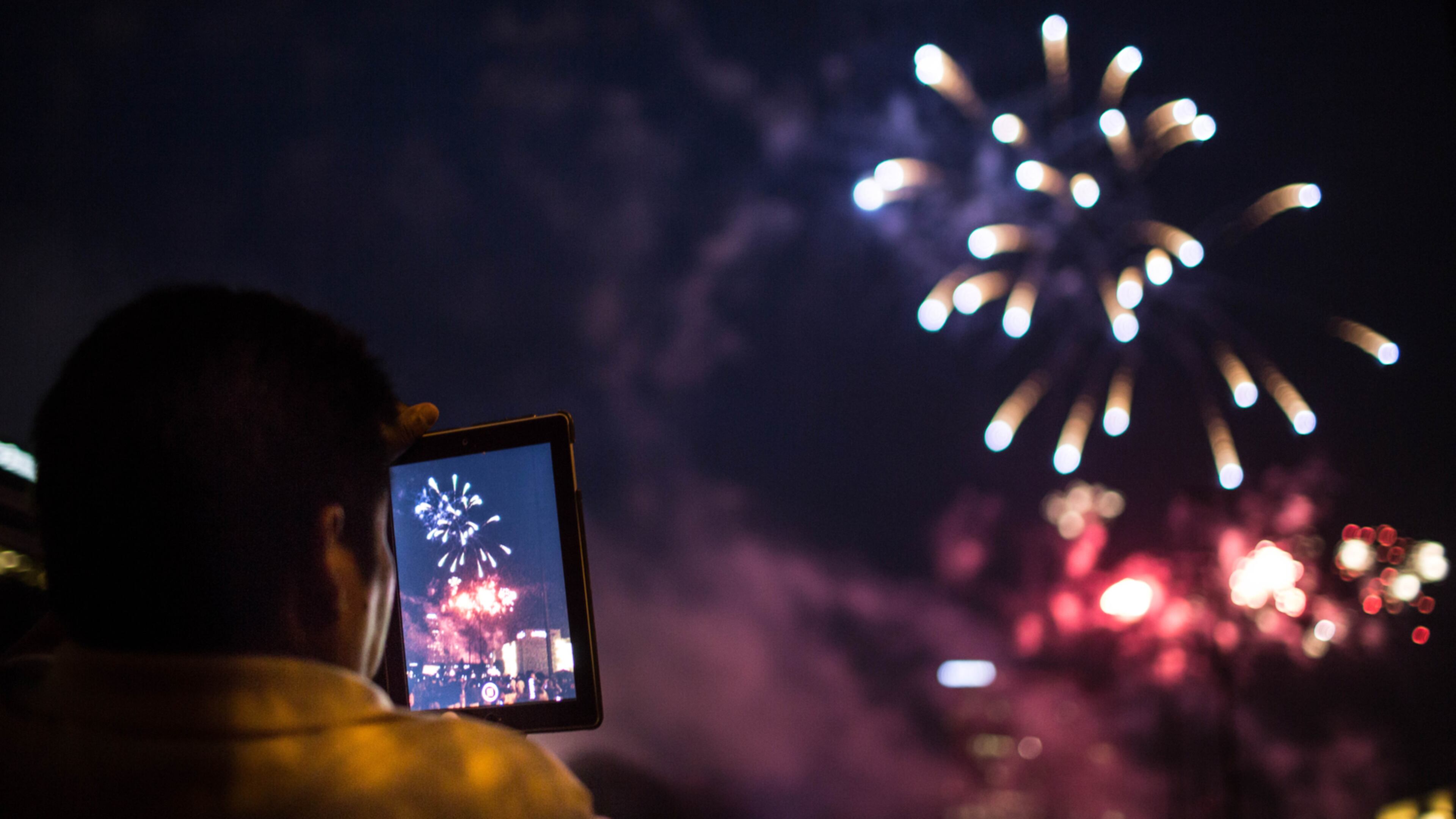 A man records a fireworks show on his iPad at Lenox Square during the annual July 4th event in 2015.