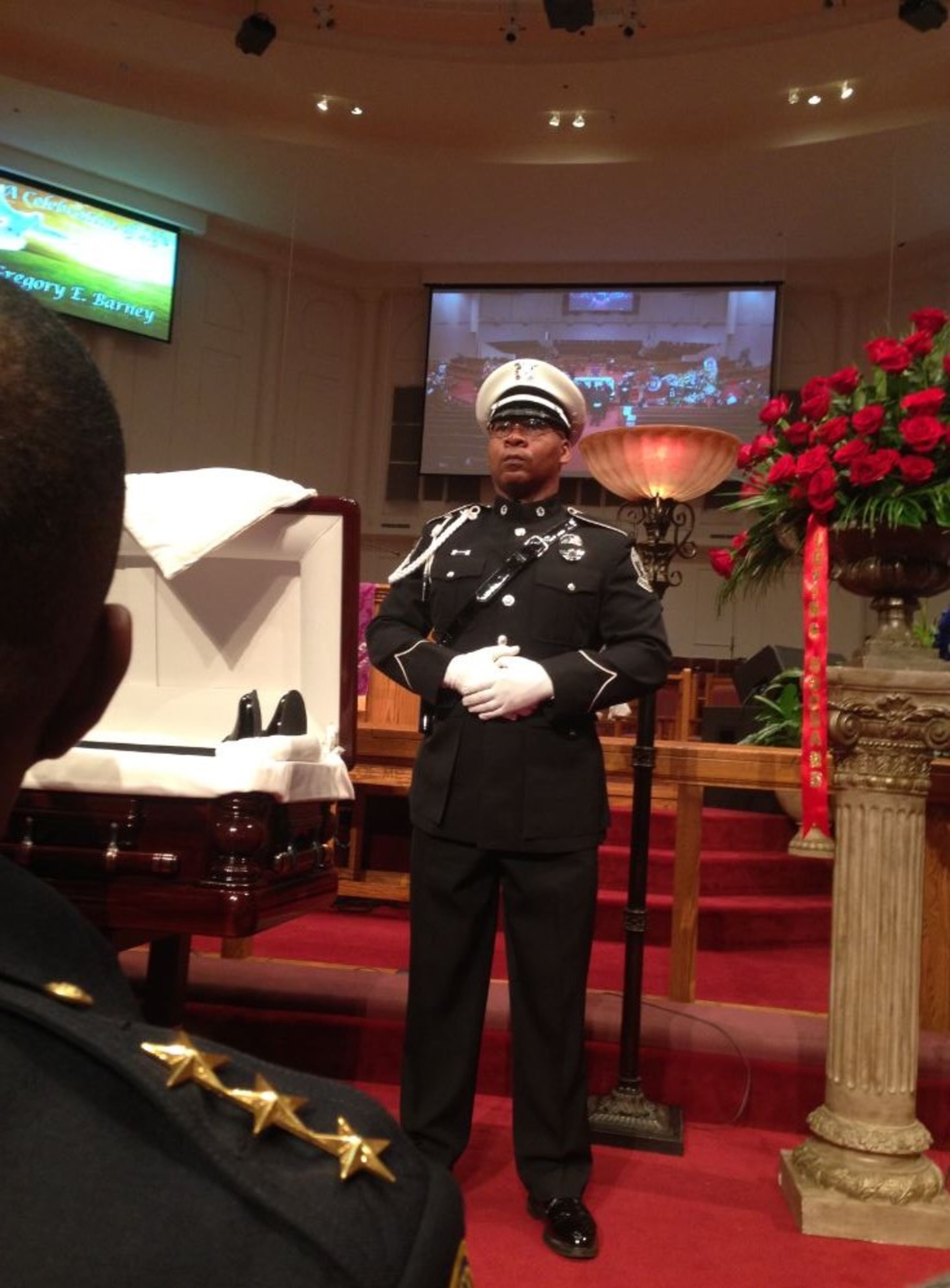 A police officer stands watch over the casket of slain Riverdale police Maj. Greg Barney at Saint Philip AME Church in DeKalb County on Saturday, Feb. 20, 2016. GRACIE STAPLES / GRACIE.STAPLES@AJC.com