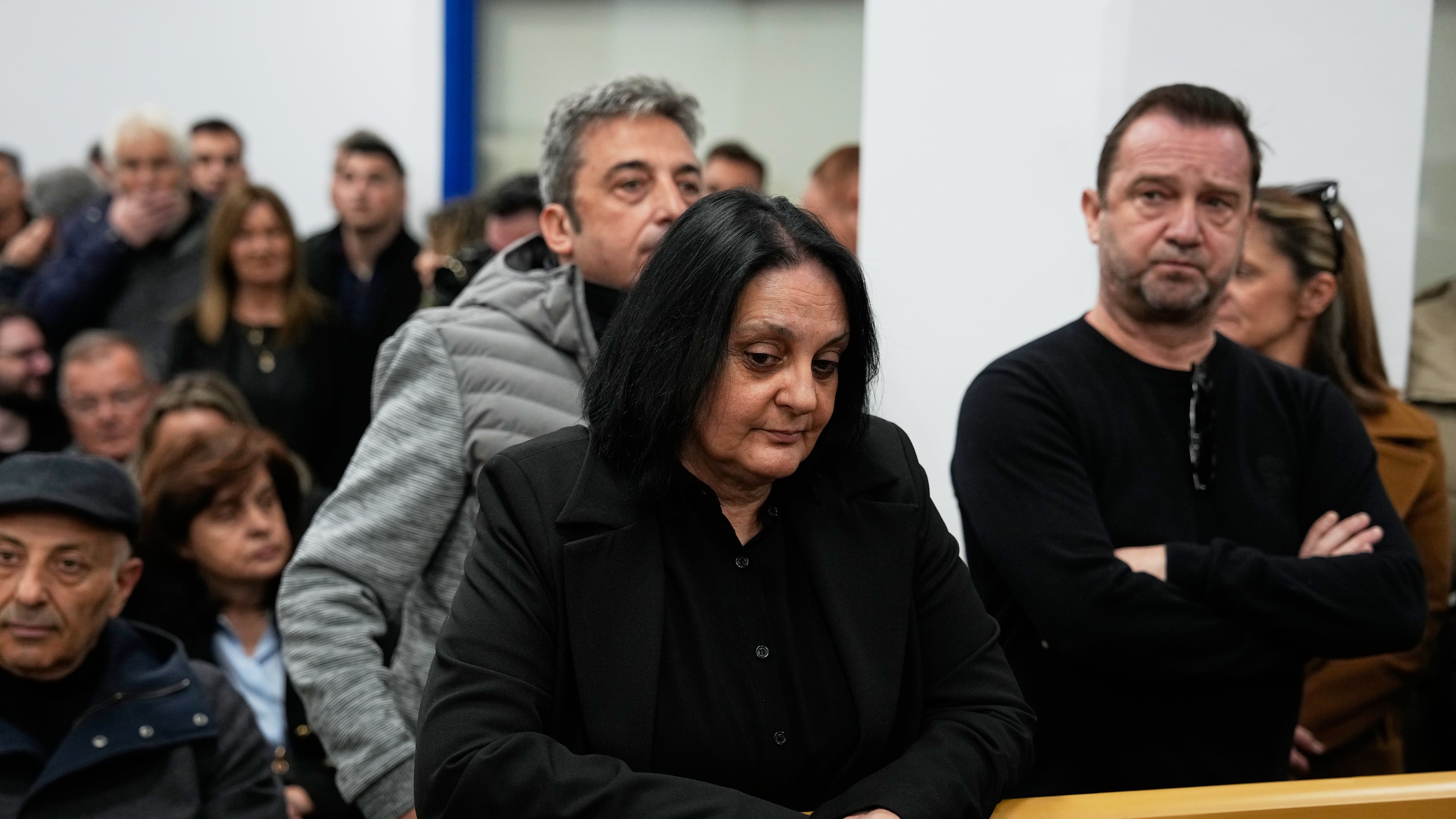 Relatives of victims of the Tempi train crash wait for the trial at the court in Larissa, Greece, Monday, March 23, 2026. (AP Photo/Thanassis Stavrakis)