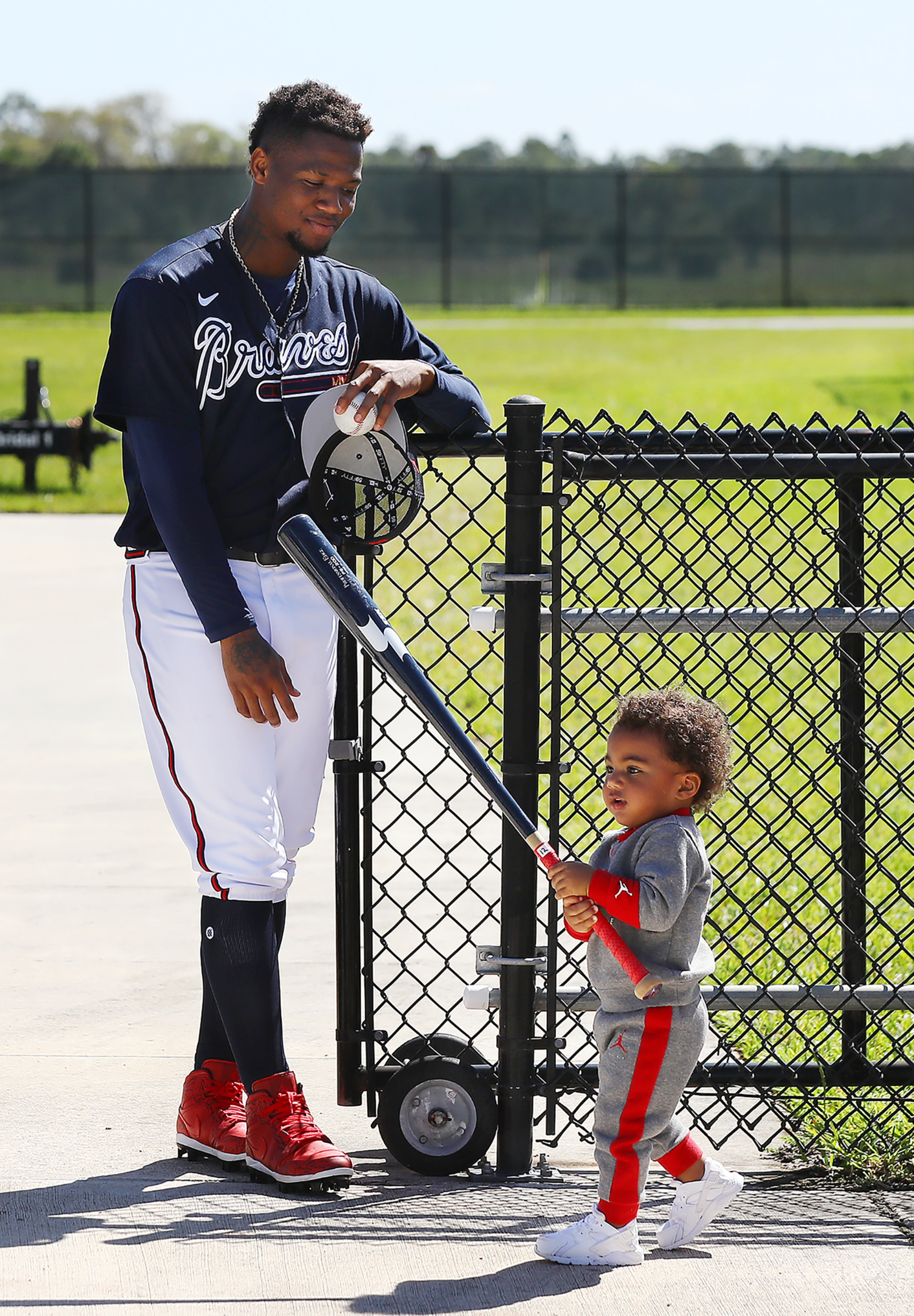 Braves outfielder Ronald Acuna looks on admiringly as his son Ronald Acuna Jr. II plays with his bat during some family time after he finishes up batting practice during Spring Training on Thursday, March 17, 2022, in North Port. “Curtis Compton / Curtis.Compton@ajc.com”