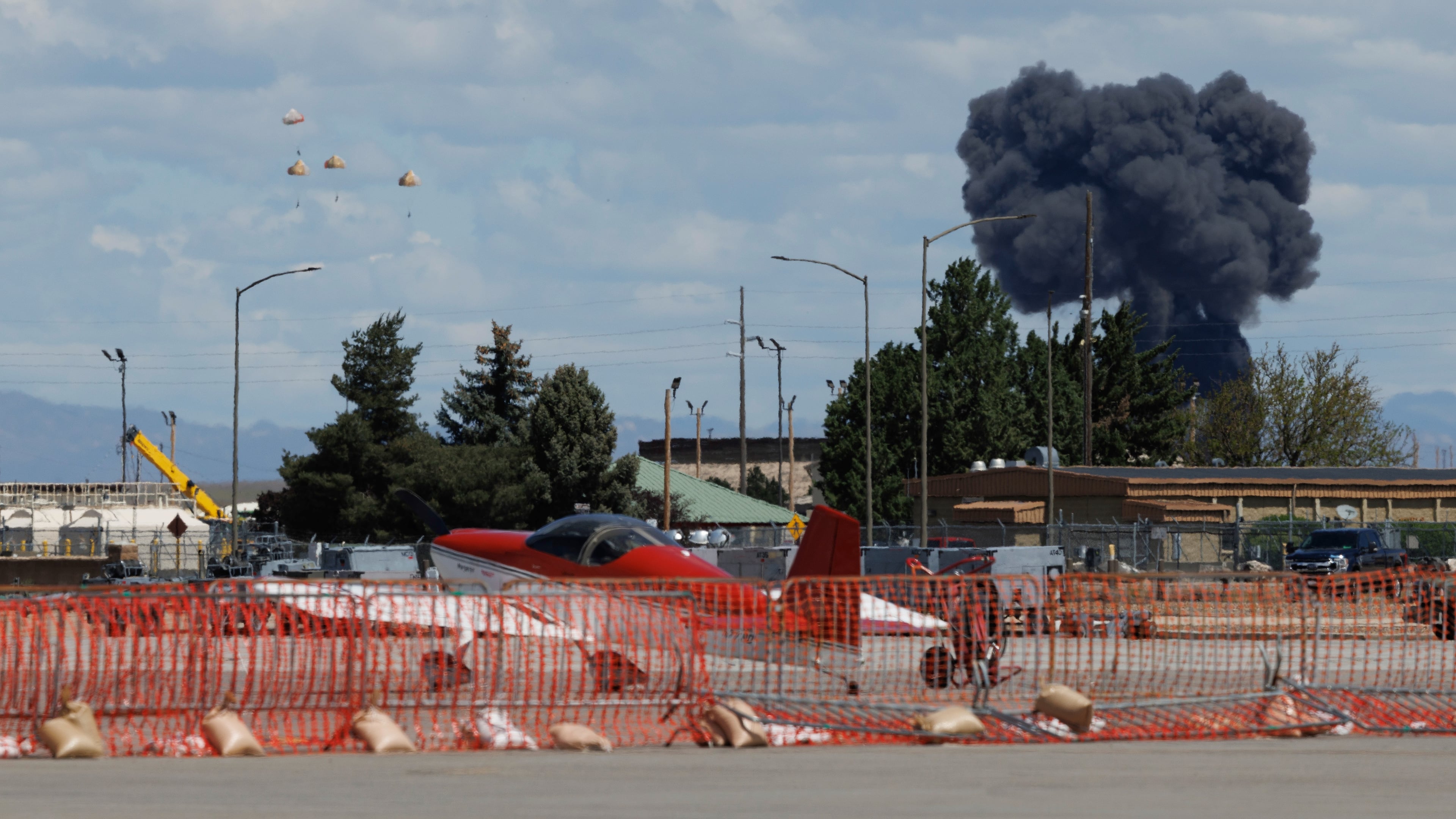 Crew members parachute to the ground, left, following a collision between two U.S. Navy planes during an air show at the Mountain Home Air Force Base, Sunday, May 17, 2026, near Mountain Home, Idaho. (Henk Zuurbier via AP)