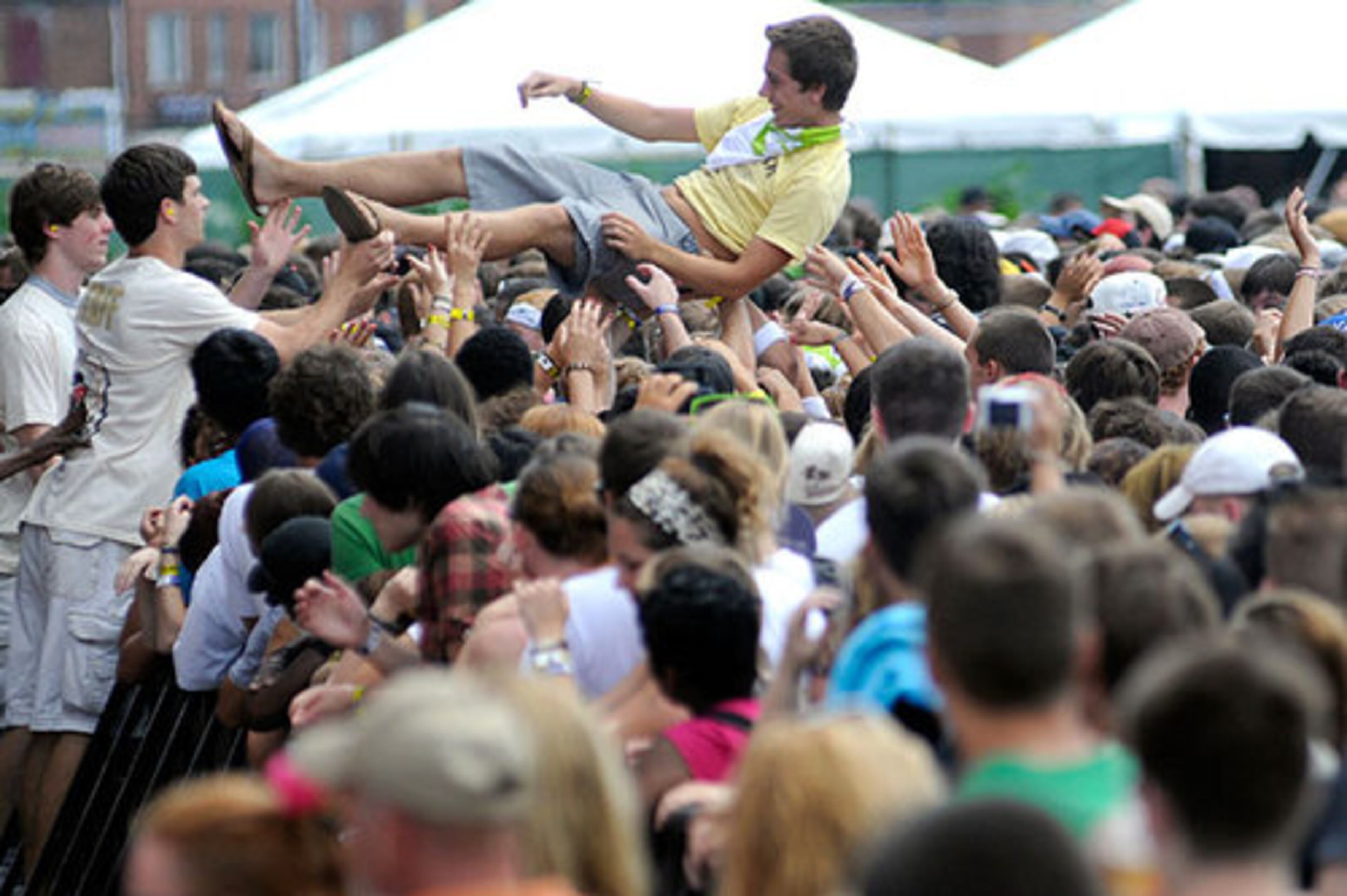 Music fans push a crowd surfer to the front as rapper Lupe Fiasco performs.