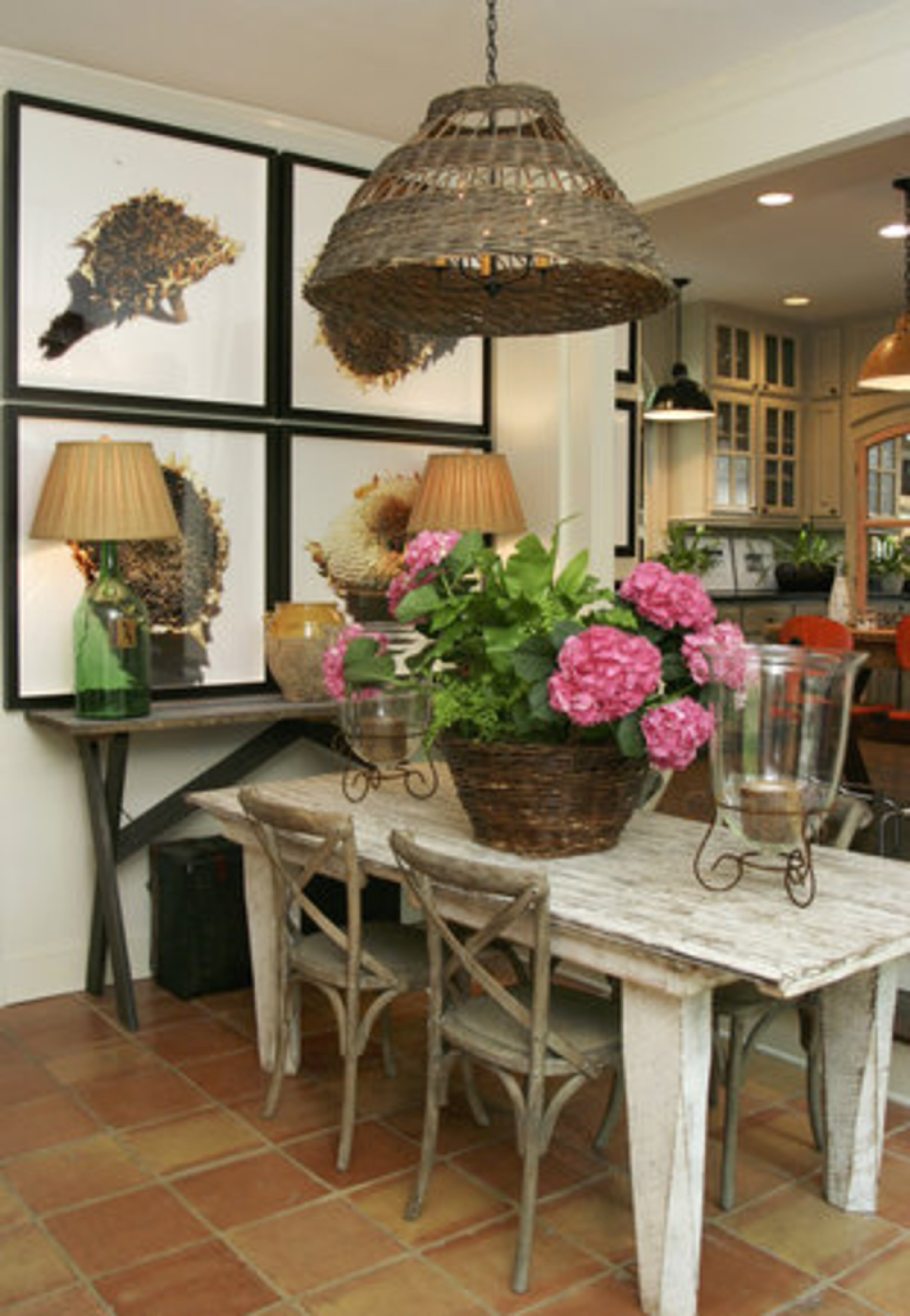 Mary designed the console in the dining room by using an old barn door. The lamps are repurposed wine vats and the light fixture was once used to catch chickens. The wall displays the "Sunflower Series" by photographer Jeff Jones.