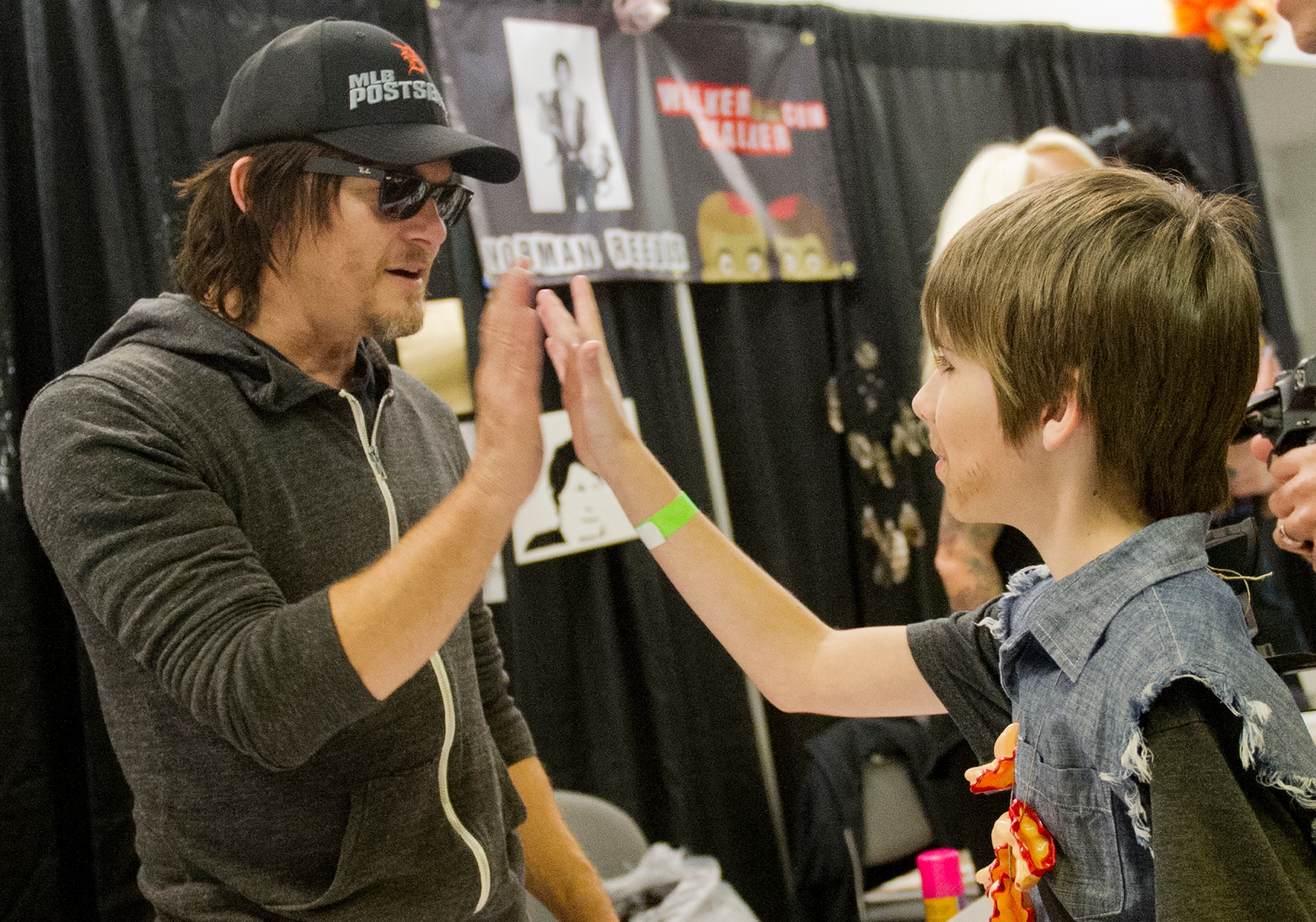 Norman Reedus (left), who plays Daryl on "The Walking Dead," gives a high-five to Jeremy Joukema during Walker Stalker Con at the Atlanta Convention Center at AmericasMart on Nov. 2, 2013.