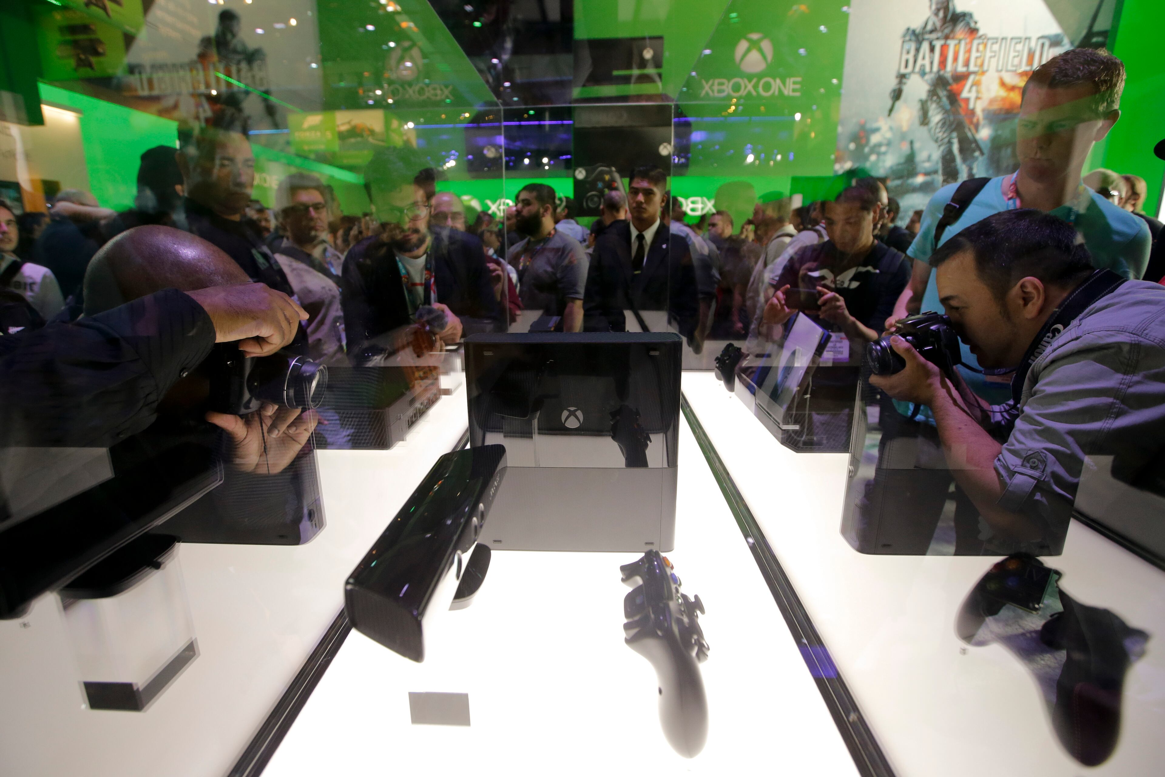 Show attendees take pictures of the Xbox 360 and Xbox One at the Microsoft booth during the Electronic Entertainment Expo, in Los Angeles, Tuesday, June 11, 2013. (AP Photo/Jae C. Hong)