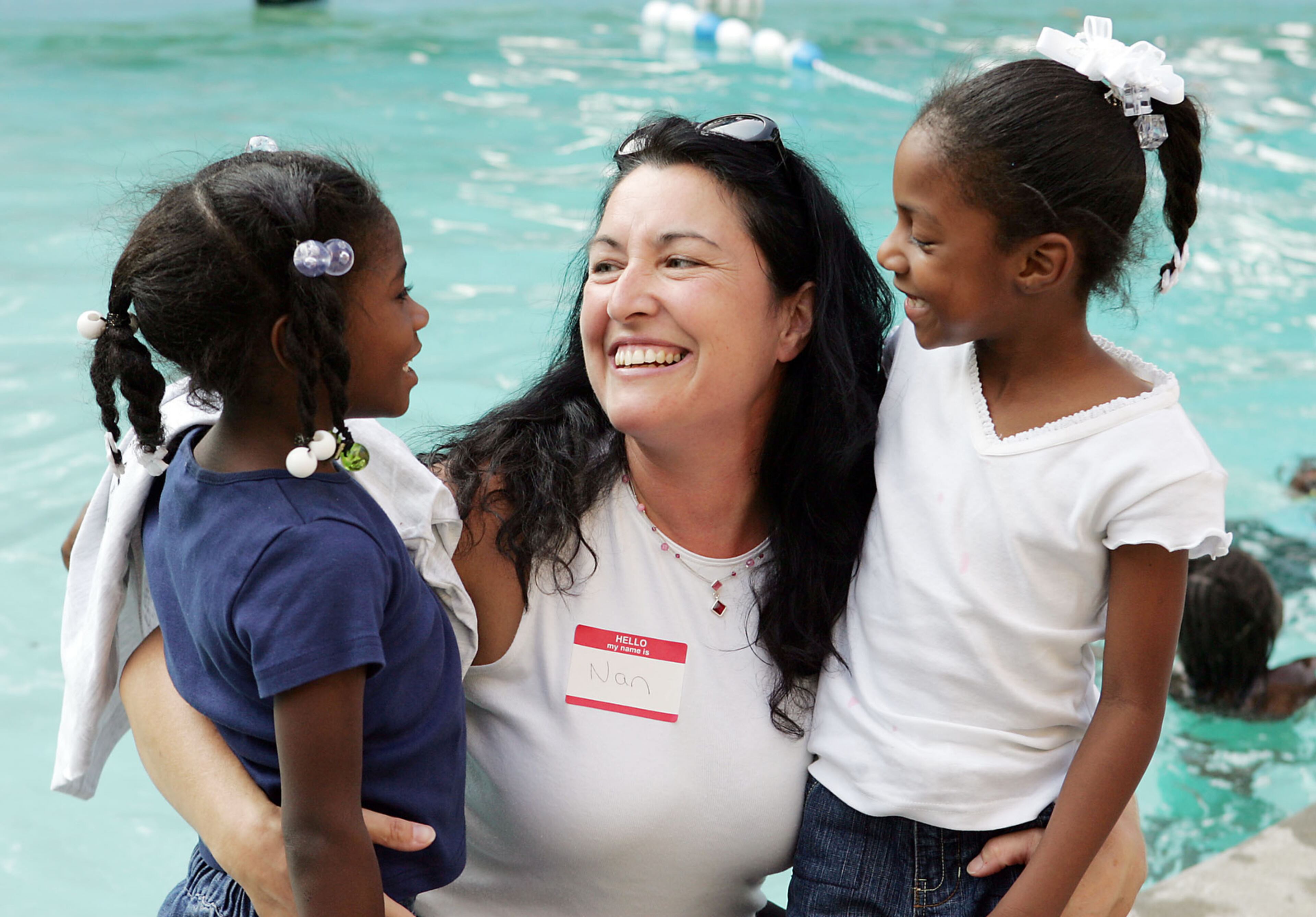 050913- L to R, Terriana Johnson, 5, Nan Morgan, and Kennedy Hagan, 5. Morgan is a volunteer helping their family, and the girls are cousins in an extended family from New Orleans that is getting into a new apartment here with Sherry Johnson. Hurricane Katrina evacuees congregate for dinner at the pool of the Studio Six hotel in Marietta. Several local churches, with the help of volunteers, have been providing meals and services there. BOB ANDRES/STAFF