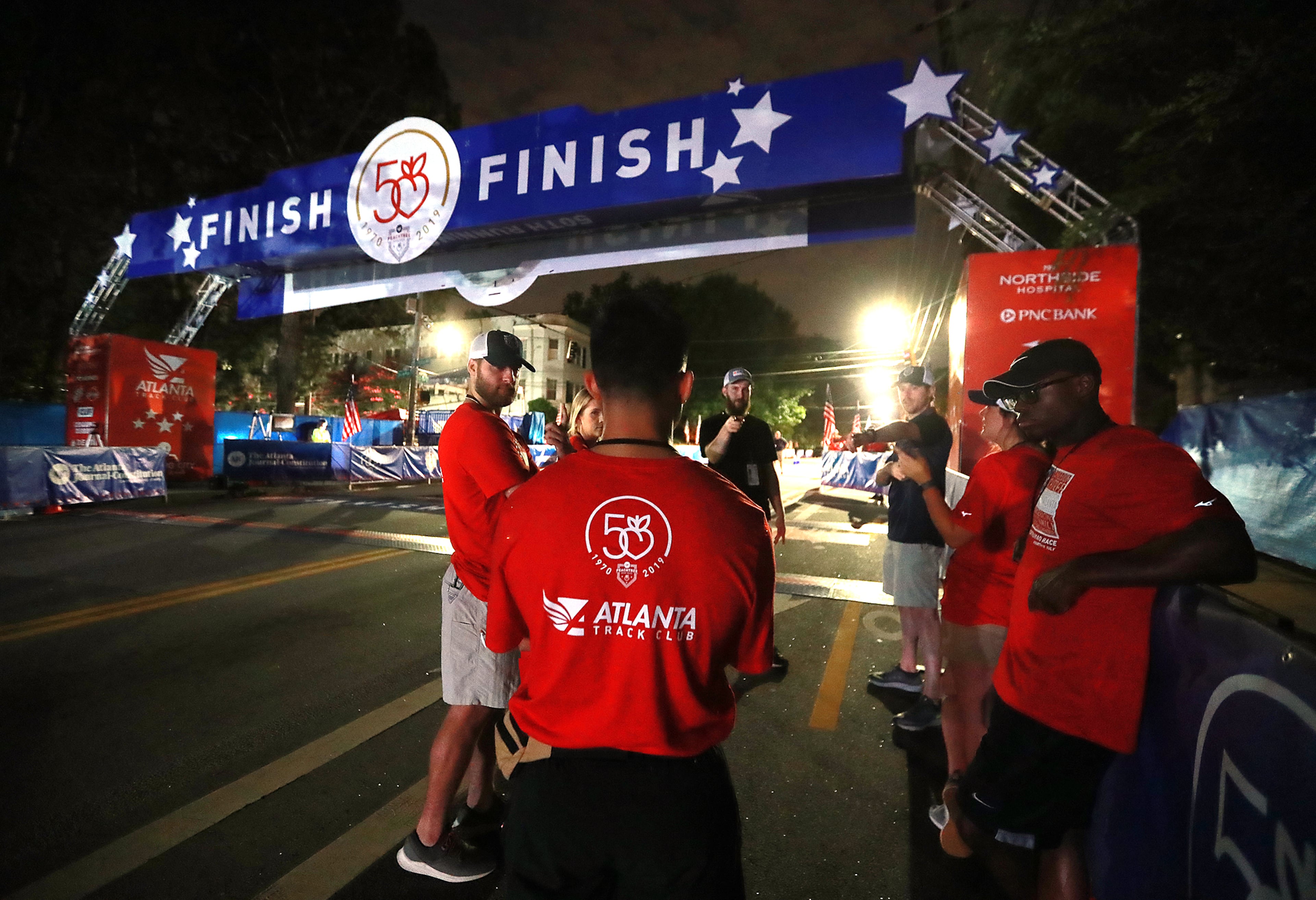 July 4, 2019 Atlanta: Atlanta Track Club volunteers gather at the finish line for a meeting while preparing for the start of the AJC Peachtree Road Race on Thursday, July 4, 2019, in Atlanta. Curtis Compton/ccompton@ajc.com