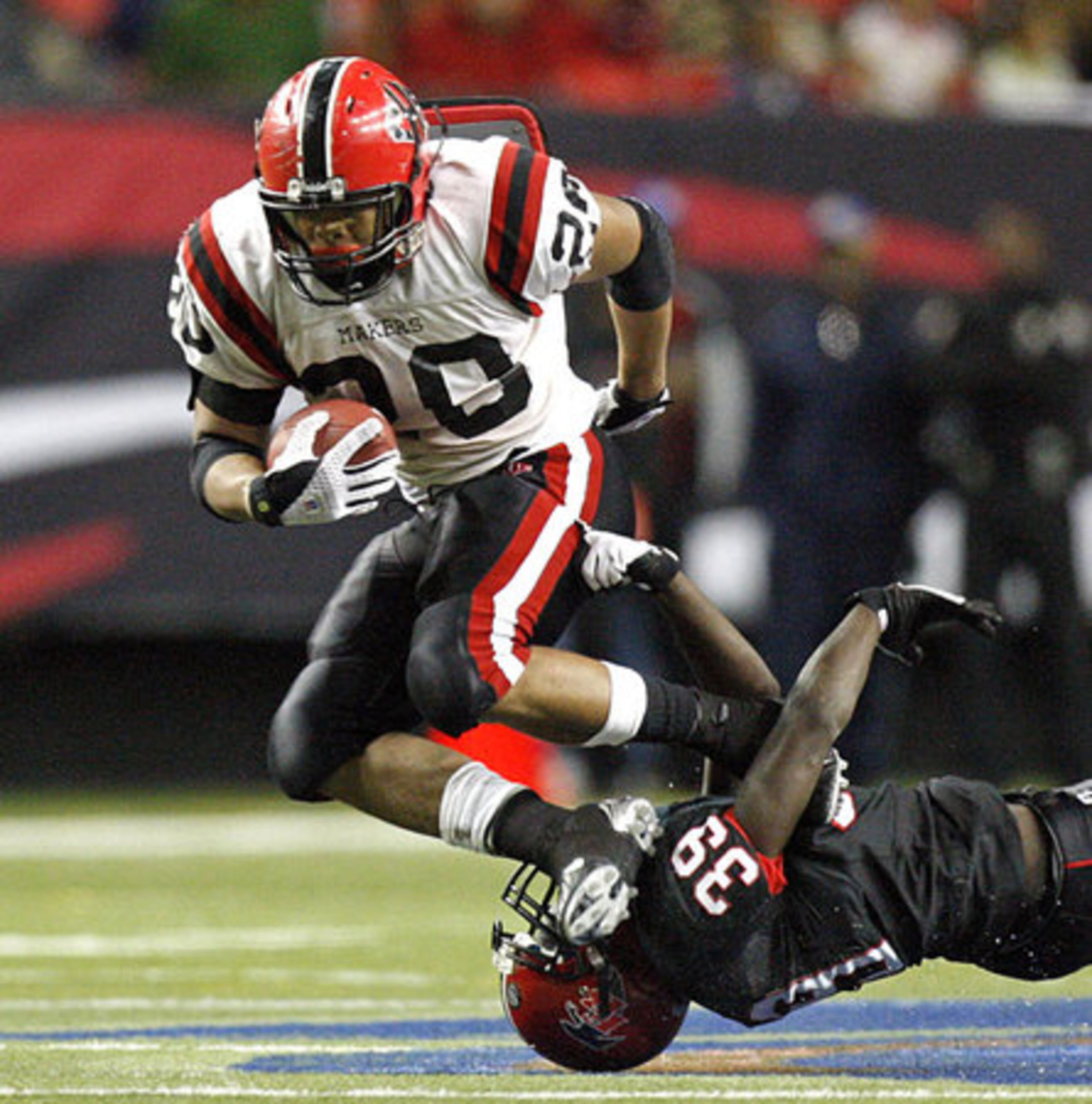 Cairo running back Reginald Bryant (20) leaps to get by the defense of Flowery Branch's Sidney Cheeks (39.