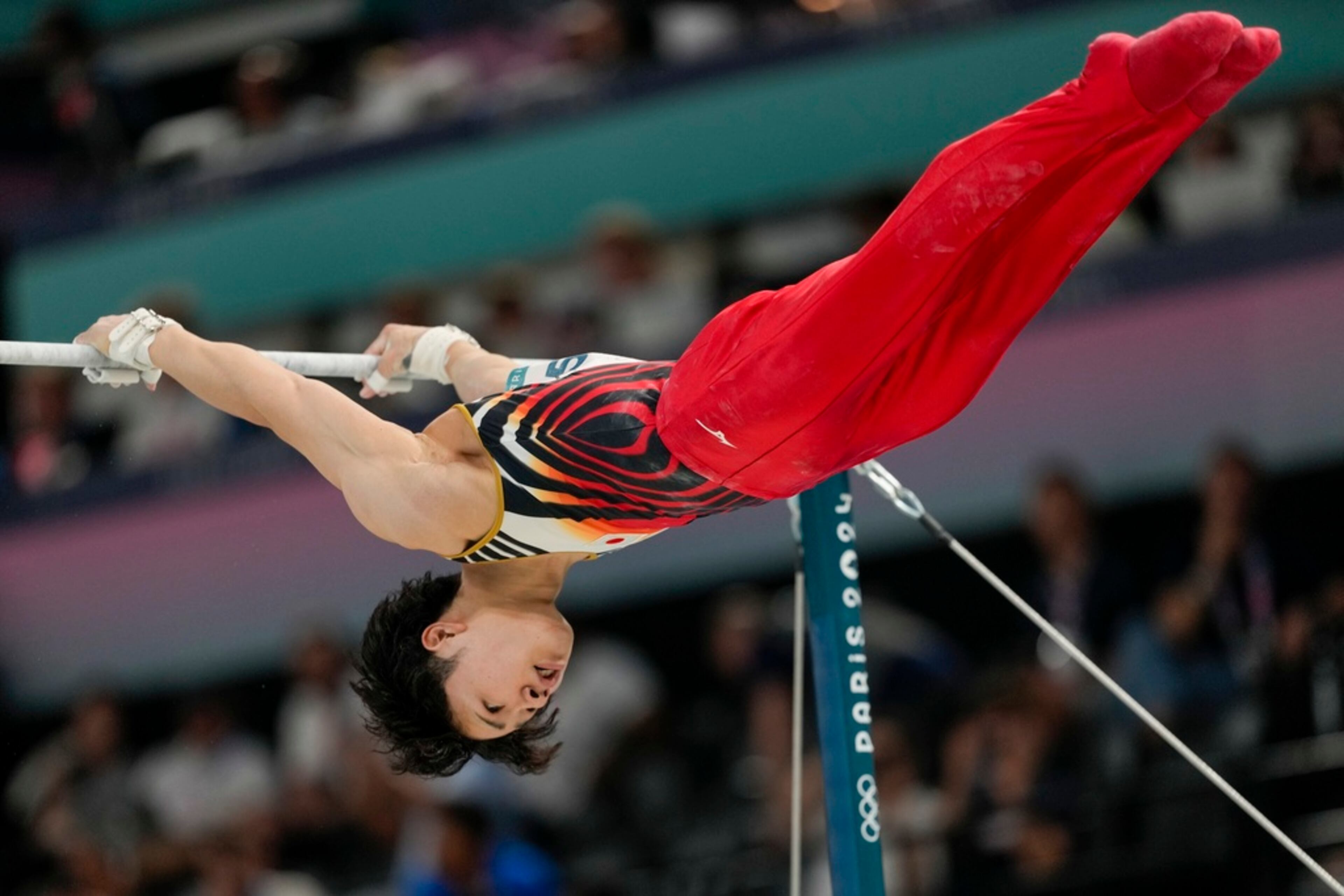 Shinnosuke Oka, of Japan, performs on the high bar during the men's artistic gymnastics team finals round at Bercy Arena at the 2024 Summer Olympics, Monday, July 29, 2024, in Paris, France. (AP Photo/Charlie Riedel)