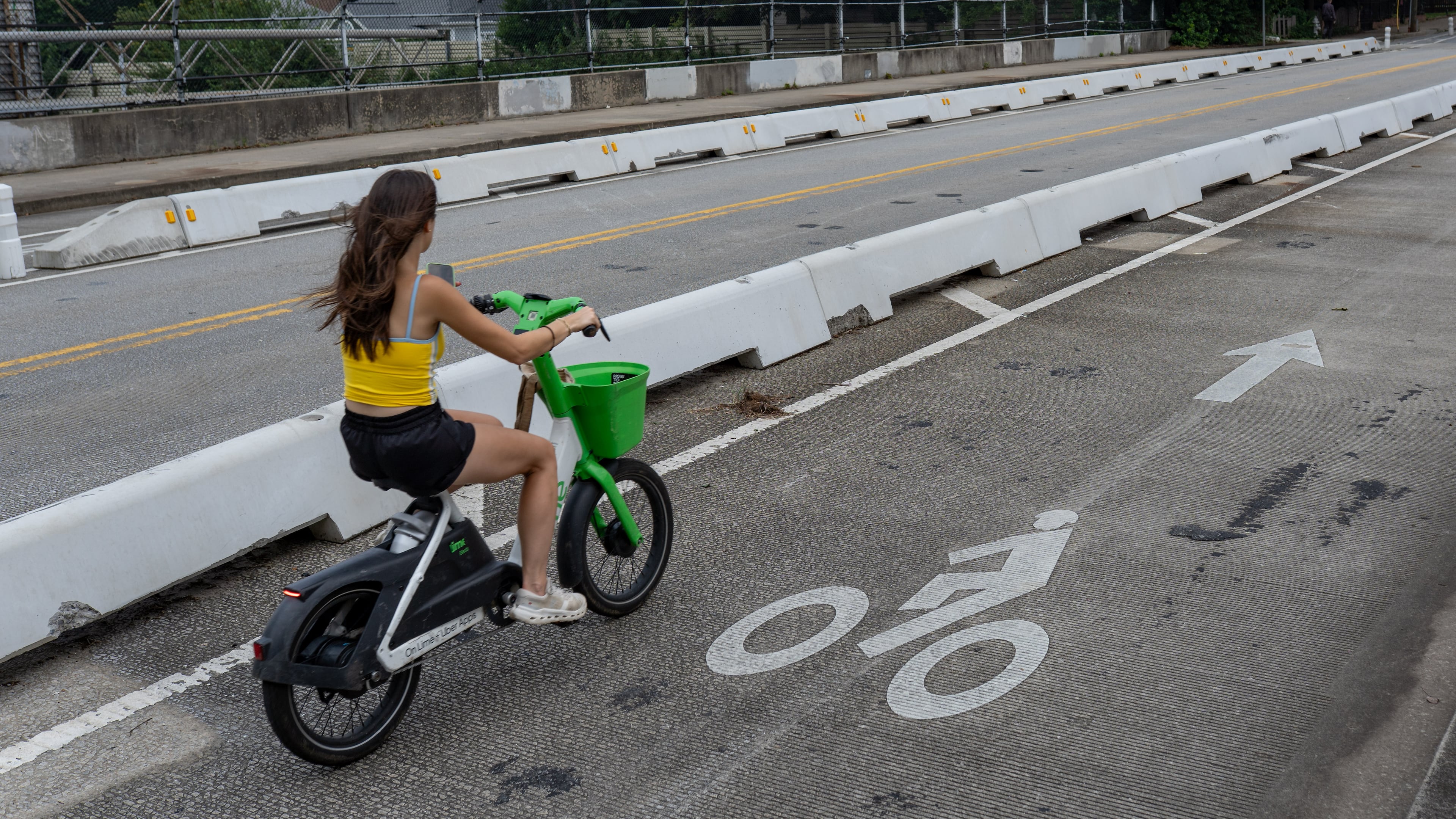 A woman rides a bicycle inside the protected bike lane along Cherokee Street on Thursday, July 30, 2026. (Ben Hendren for the AJC)