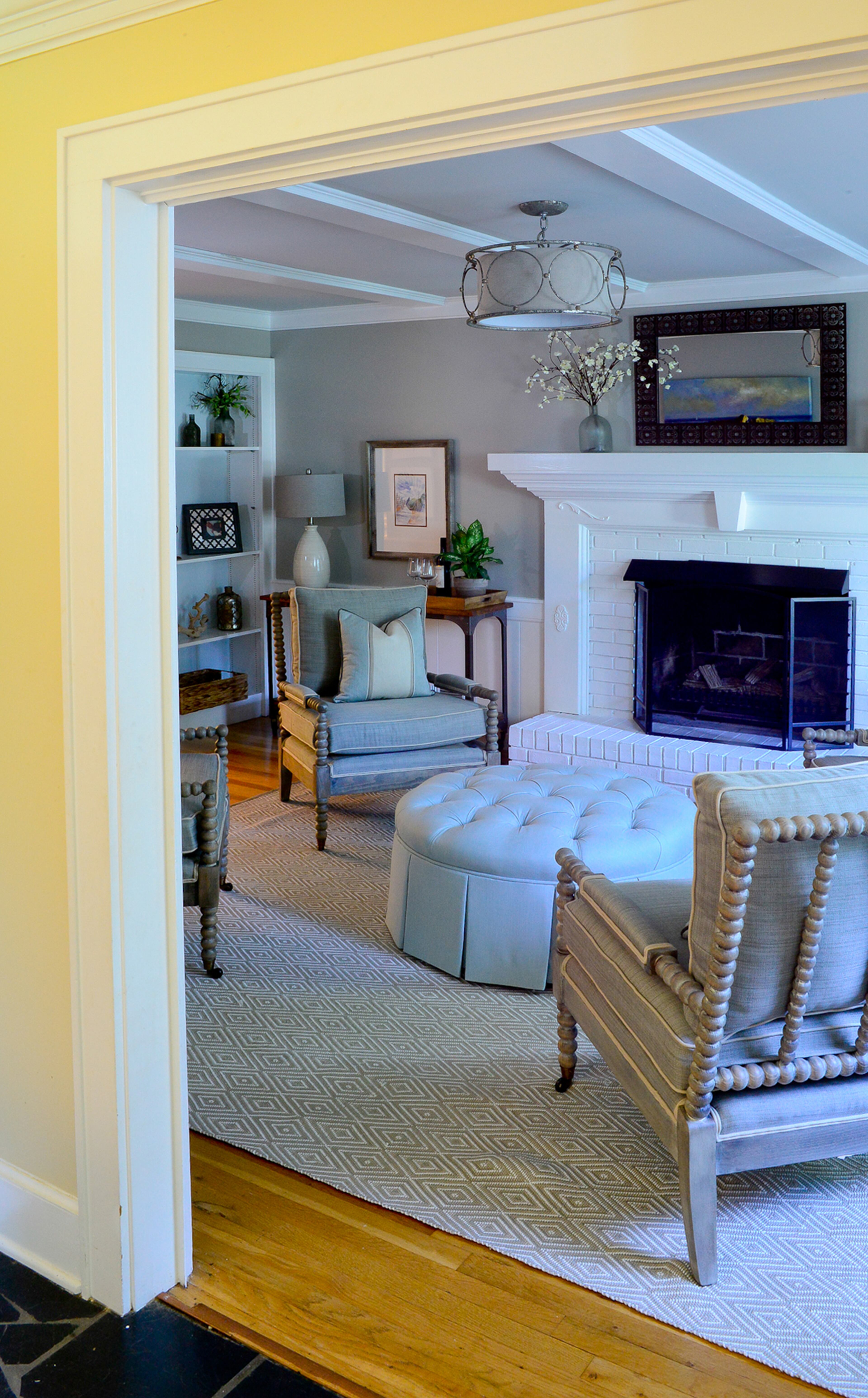 The living room was redone with a color palette of grays and blues. The homeowners can enjoy the fireplace when sitting in the new spindle chairs by DR Kinkaid.