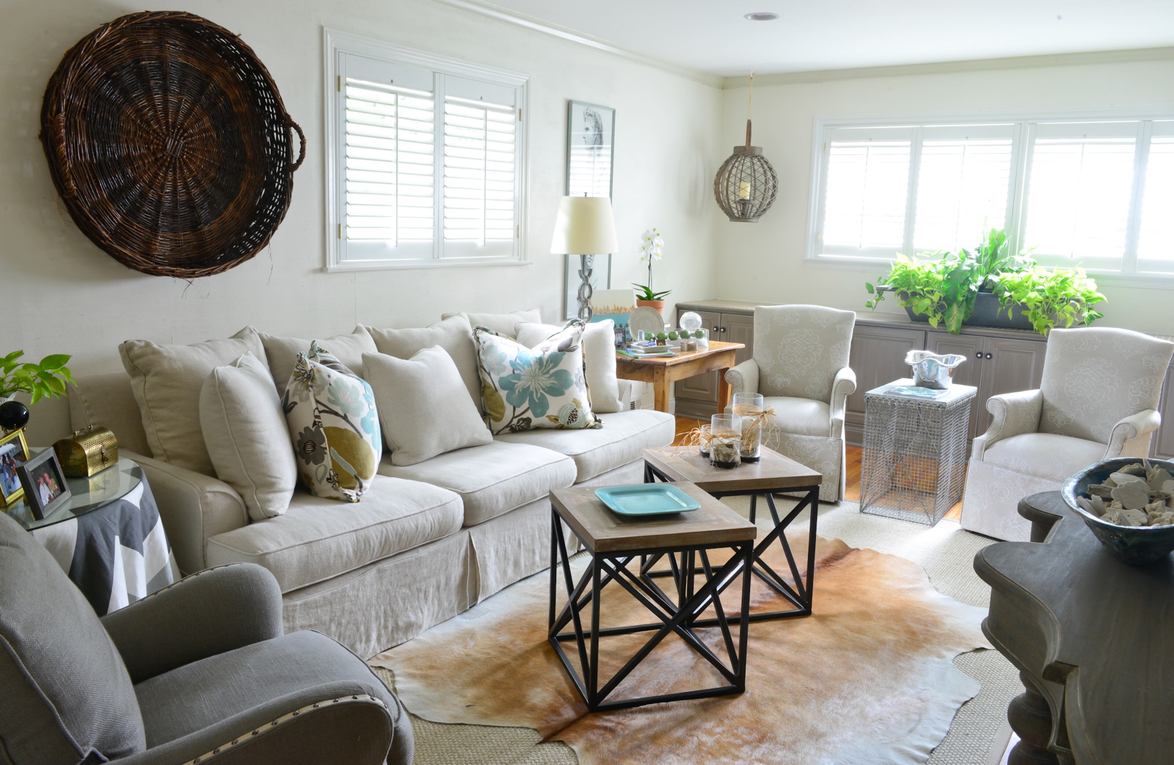 The living room's oblong shape presented decorating challenges, but larger statement-making pieces, such as a basket on the wall, helped balance the space, Betsy Clay said. Lanterns with candles, from Antiques & Beyond, hang above a wall of cabinets that store Christmas china and other items. For a new look, the doors were remade, distressed and painted, and molding was added to the bottom of the cabinet.