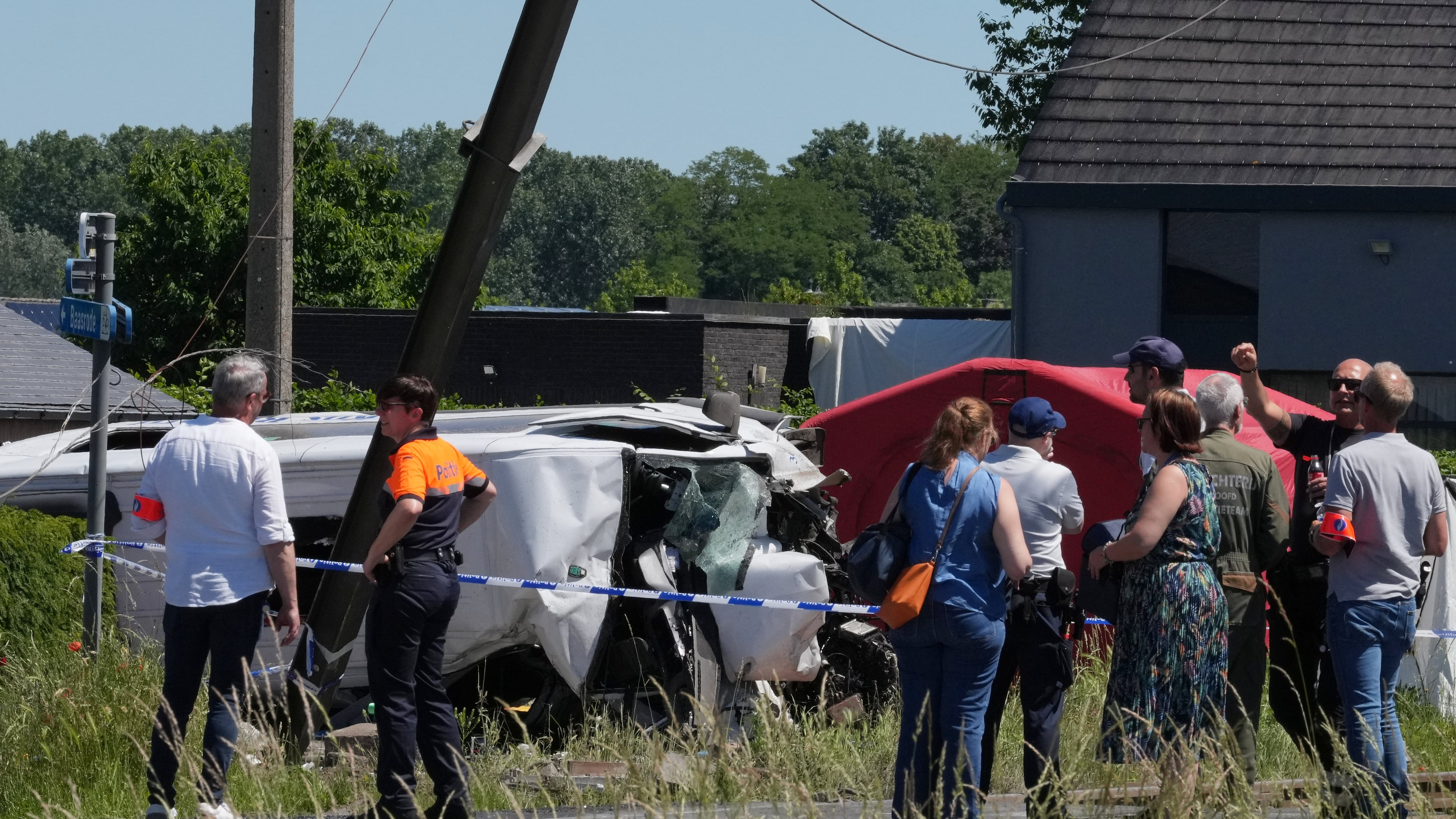 Police and residents gather around a level crossing where a train collided with a van in Buggenhout, Belgium, Tuesday, May 26, 2026. (AP Photo/Marius Burgelman)