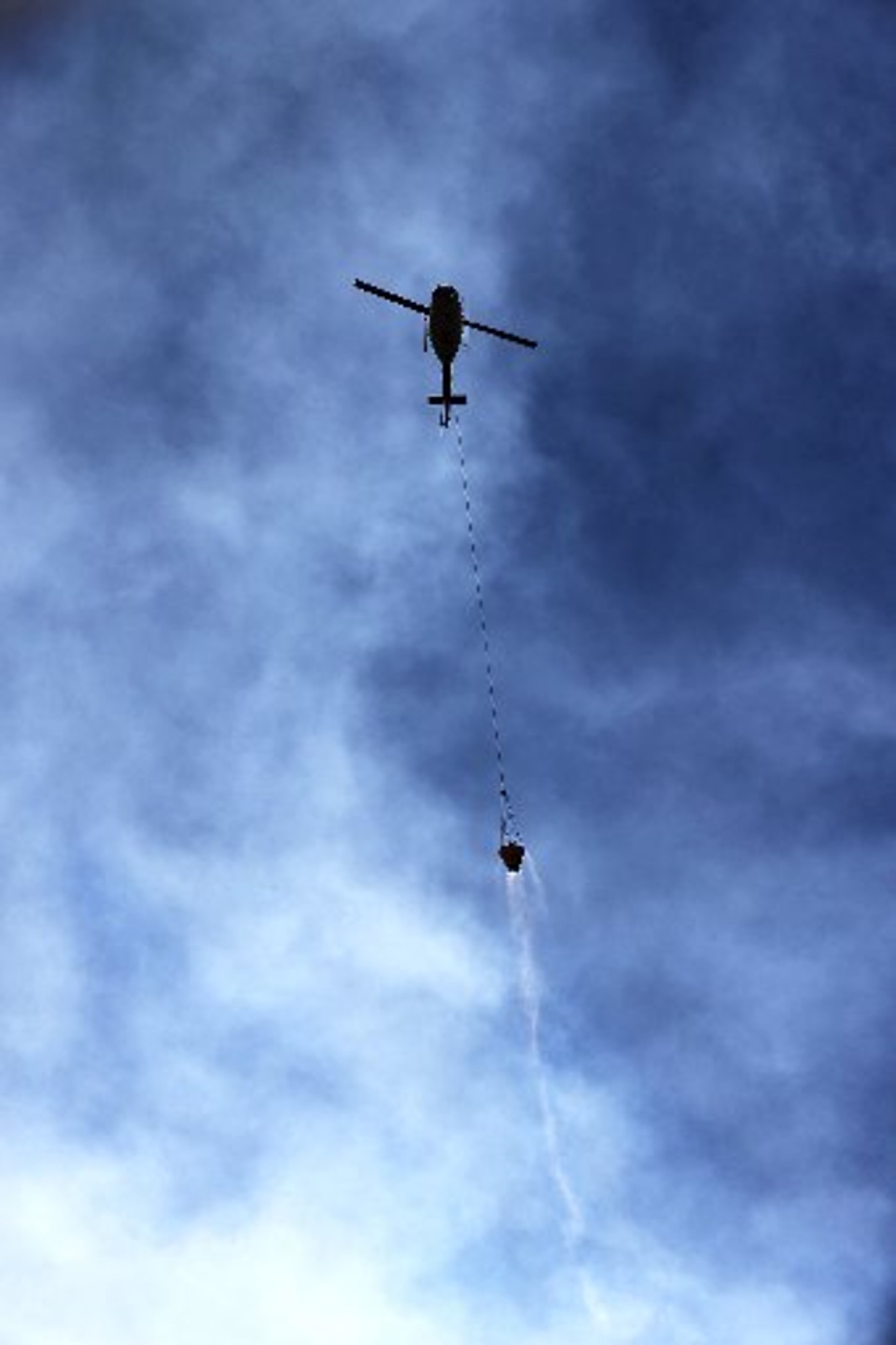 A helicopter is surrounded by smoke while flying a bucket of water to fight the Rock Mountain fire Monday. CURTIS COMPTON / CCOMPTON@AJC.COM