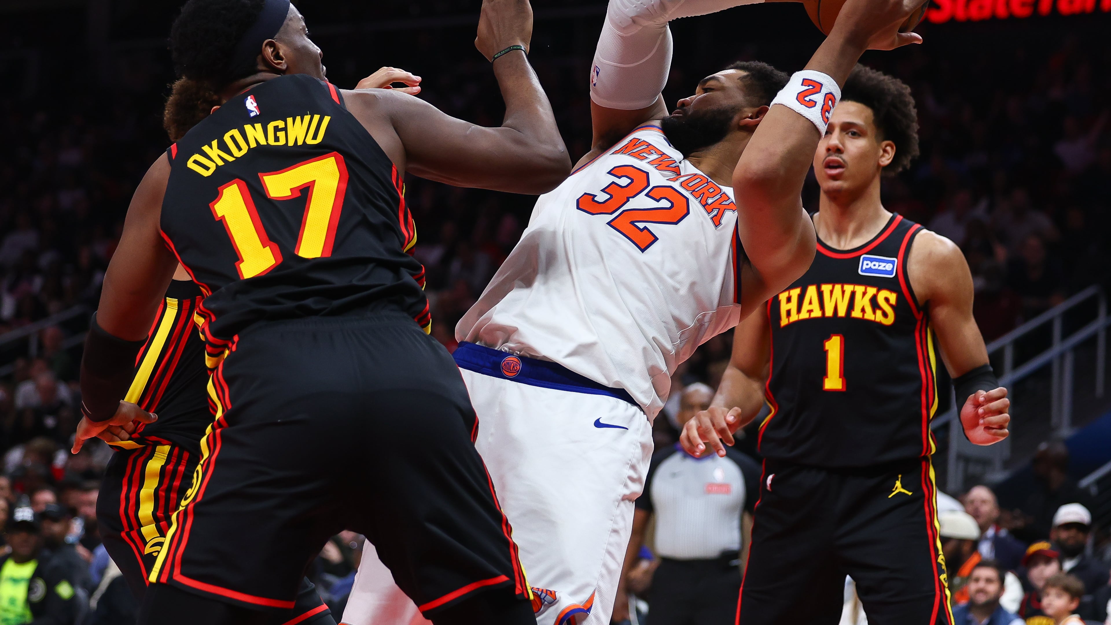 New York Knicks center Karl-Anthony Towns (32) rebounds against Atlanta Hawks forwards Onyeka Okongwu (17) and Jalen Johnson (1) during the second half of an NBA basketball game, Monday, April 6, 2026, in Atlanta. (AP Photo/Colin Hubbard)